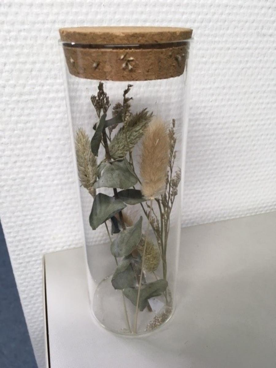 Glasware zur Innenausstattung, sog. Trockenpflanzen in einem Behältnis aus Glas, Foto siehe Anlage,
aus verschiedenen Bestandteilen zusammengesetzte Ware, bestehend aus:
- einem Glasgefäß:
- - in Form einer zylinderförmigen, oben offenen Glasröhre aus klarsichtigem, handgefertigtem
   (manuelle Glasentnahme) gewöhnlichem Glas (laut Antrag),
- - in den Abmessungen von ca. 20 cm (Höhe) x 5 cm (Durchmesser),
- - mit einem Verschluss in Form eines Korkstopfens,
- getrockneten Blumen:
- - lose in die Glasröhre eingestellt,
- im Hinblick auf die Zierwirkung herrschen die getrockneten Blumen vor, nach seiner Bedeutung
  in Bezug auf die Verwendung (Schutz der Blumen) ist das Glasgefäß charakterbestimmend; somit
  bestimmt keiner der Bestandteile den wesentlichen Charakter der zusammengesetzten Ware und
  diese ist daher der von den gleichermaßen in Betracht kommenden Positionen (0603 / 7013) in
  der Nomenklatur zuletzt genannten Position zuzuweisen.

"Glasware zur Innenausstattung, aus gewöhnlichem Glas, handgefertigt"