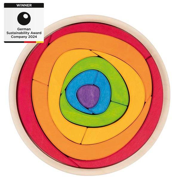 Bei dem vorliegenden Warenmuster handelt es sich um Baukastenspielzeug als Warenzusammenstellung in Aufmachung für den Einzelverkauf
- aus Holz gefertigt und vollständig bunt bemalt,
- mit abgerundeten Kanten und glatten Flächen,
- mit 13 farbigen Puzzle-/Bauteilen in unterschiedlichen, gerundeten Formen,
  etwa 3 – 17 cm lang, 
- die Teile lassen sich wie Bauklötze zum Bau von kreativen Gebilden nutzen, 
- ohne Hinweis auf Fertigung in Handarbeit,
- aufgemacht auf einer naturfarbenen Unterlage aus Holz mit erhabenem Rand,
  die den Baukastenelementen zur Aufbewahrung und zum Transport dient,
- dient der spielerischen Unterhaltung von Kindern, 
- in einem bunt bedruckten Pappkarton für den Einzelverkauf verpackt. 

Im Hinblick auf den Umfang und den Verwendungszweck sind die Bauklötze als charakterverleihend anzusehen. 

Die Ware wird zolltarifrechtlich als "Baukastenspielzeug, aus Holz, nicht handgearbeitet" eingereiht.