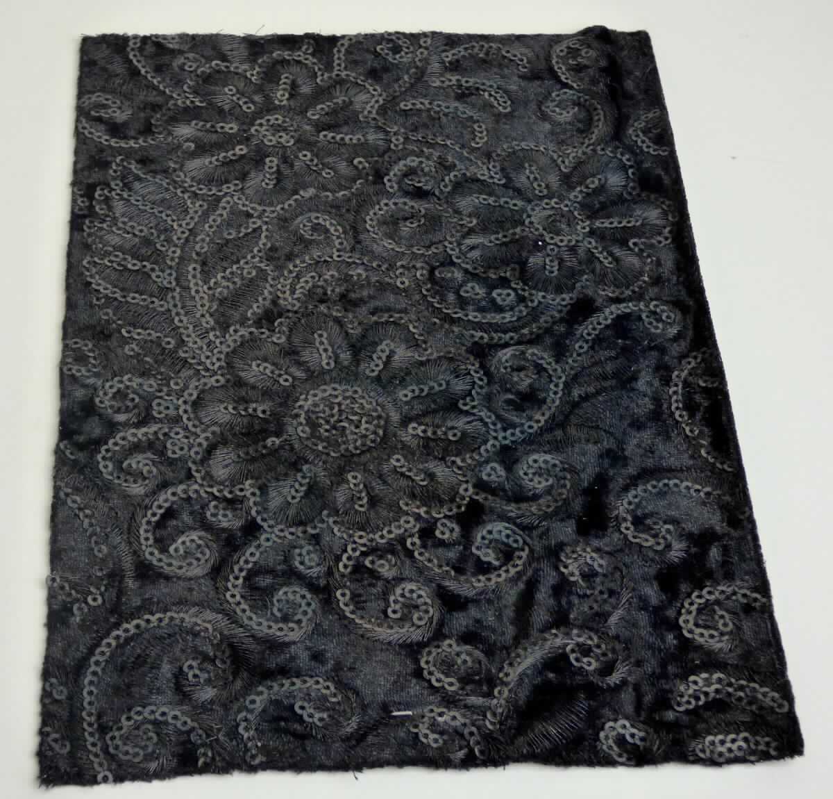 Textillaminat, sog. Obermaterial zur Schuhherstellung, Foto siehe Anlage,
- als Meterware, mit einer Breite von laut Antrag 130 cm,
- laut Untersuchungsergebnis:
-- aus zwei mit ihrer ganzen Fläche aufeinander liegenden und so miteinander durch Kleben verbundenen Lagen:
--- mit einer Oberlage (Schauseite):
---- aus einer Stickerei mit einem Stickgrund aus Samtgewirke aus synthetischen Chemiefasern (laut Antrag 
      Polyester), 
---- zusätzlich mit aufgestickten Pailletten (Applikationen) versehen,
---- maschinell hergestellt,
---- keine Ätzstickerei,
--- mit einer Unterlage:
---- aus einem einfarbigen Gewebe,
- mit einem Wert der Stickerei von laut Antrag weniger als 17,50 Euro je kg Eigengewicht,
- die die Schauseite bildende Stickerei verleiht der Ware insbesondere im Hinblick auf die Verwendung als
  Obermaterial für Schuhe ihren wesentlichen Charakter.

"Stickerei als Meterware, keine Ätzstickerei und Stickerei mit herausgeschnittenem Grund, aus Chemiefasern,
 mit einem Wert von weniger als 17,50 Euro je kg Eigengewicht, nicht handgearbeitet"