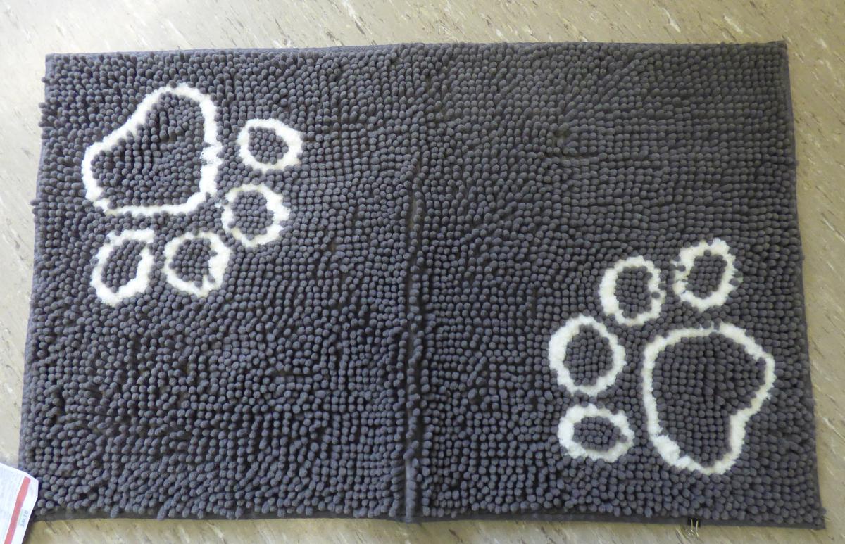 Fußbodenbelag, Foto siehe Anlage,
- rechteckig, mit den Abmessungen von laut Antrag 80 cm x 50 cm,
- aus synthetischen Spinnstoffen (laut Antrag 100 % Polyester),
- getuftet (Nadelflor),
- mit einem Grund aus einem Gewebe und einem nachträglich in das Grundgewebe eingezogenen
  Flor aus Chenillegarnen und gezwirnten Garnen (als stilisierte Pfotenabdrücke),
- an den Rändern mit schmalen Gewebestreifen eingefasst (damit konfektioniert; keine Fliese),
- auf der Rückseite rutschfest mit laut Antrag Kautschuk (TPR) überzogen,
- erfüllt die Bedingungen zur Einreihung als Fußbodenbelag.

"Fußbodenbelag, aus Spinnstoffen, getuftet (Nadelflor), konfektioniert, aus synthetischen 
 Spinnstoffen (Polyester), keine Fliese"