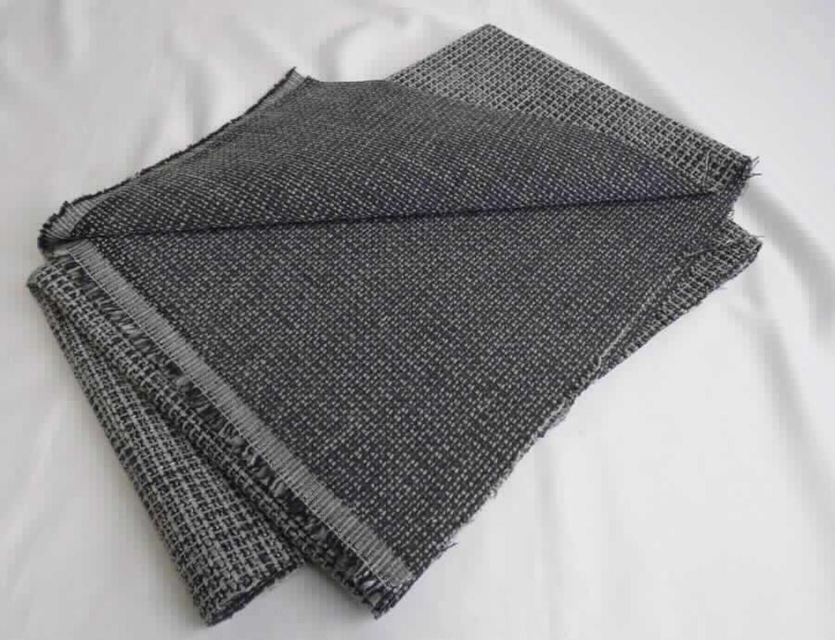 Gewebe, sog. Möbelbezugsstoff, Foto siehe Anlage, 
- als Meterware, mit einer Breite von mehr als 30 cm, 
- laut Untersuchungsergebnis: 
- - aus dünnen Kett- und Schussgarnen aus synthetischen Spinnfasern (laut Antrag Polyester), dicken, grauen
    Kett- und Schussgarnen (Chenille) aus synthetischen Spinnfasern (laut Antrag Polyester) sowie weiß-schwarzen 
    Kett- und Schussgarnen (Effektzwirne) aus zwei Garnen aus synthetischen Filamenten (laut Antrag Polyester) 
    und einem Garn aus synthetischen Spinnfasern (Polyester und Polyacryl), 
- - mit einem Gesamtanteil an: 
- - - synthetischen Spinnfasern von ca. 93 - 94 GHT (somit keine Ware der Unterposition 5512 9900), davon ca.
      90 GHT Spinnfasern aus Polyester,
- - - synthetischen Filamenten von ca. 6 - 7 GHT, 
- - buntgewebt, 
- - in Musterbindung, 
- - auf der Rückseite mit dem bloßen Auge nicht wahrnehmbar dünn mit Kunststoff bestrichen bzw. getränkt.

"Gewebe aus synthetischen Spinnfasern, mit einem Anteil an diesen Spinnfasern von mehr als 85 GHT, mit einem 
 Anteil an Polyester-Spinnfasern von mehr als 85 GHT, buntgewebt"
