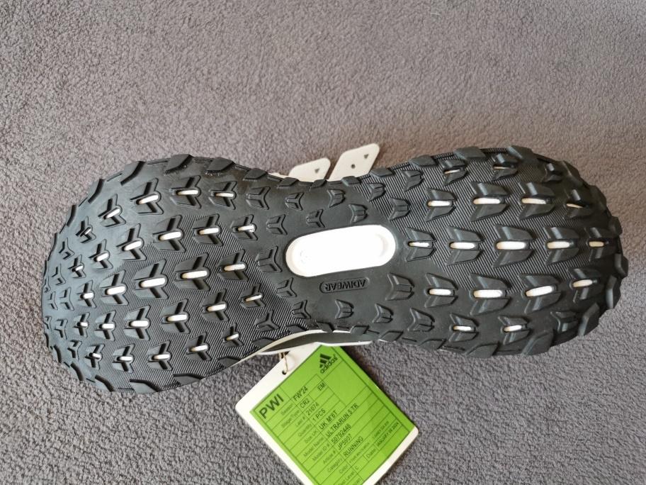 Trainingsschuhe, sog. Laufschuh Ultrarun 5 TR, Art. JP5907, Silhouetten-Nr. 67883, Leisten-Nr. 21074,
Größe UK 8,5, Foto siehe Anlage,
- mit Laufsohlen aus laut Antrag Kautschuk,
- mit Oberteil aus Spinnstoff,
- auf das Oberteil sind Verstärkungsteile aus Kunststoff und Spinnstoff aufgesetzt, zusätzlich mit Kunst-
  stoff verstärkt,
- mit Schnürsenkelverschluss,
- seitlich und auf der Lasche mit Firmenlogos versehen,
- im Bereich der Ferse mit einer Anziehhilfe,
- lassen aufgrund von Form, Schnitt, Aussehen und Material erkennen, dass sie für die Ausübung
  einer bestimmten Sportart (Laufen) gestaltet sind.

"Schuhe (Trainingsschuhe) mit Laufsohlen aus Kautschuk und Oberteil aus Spinnstoffen"