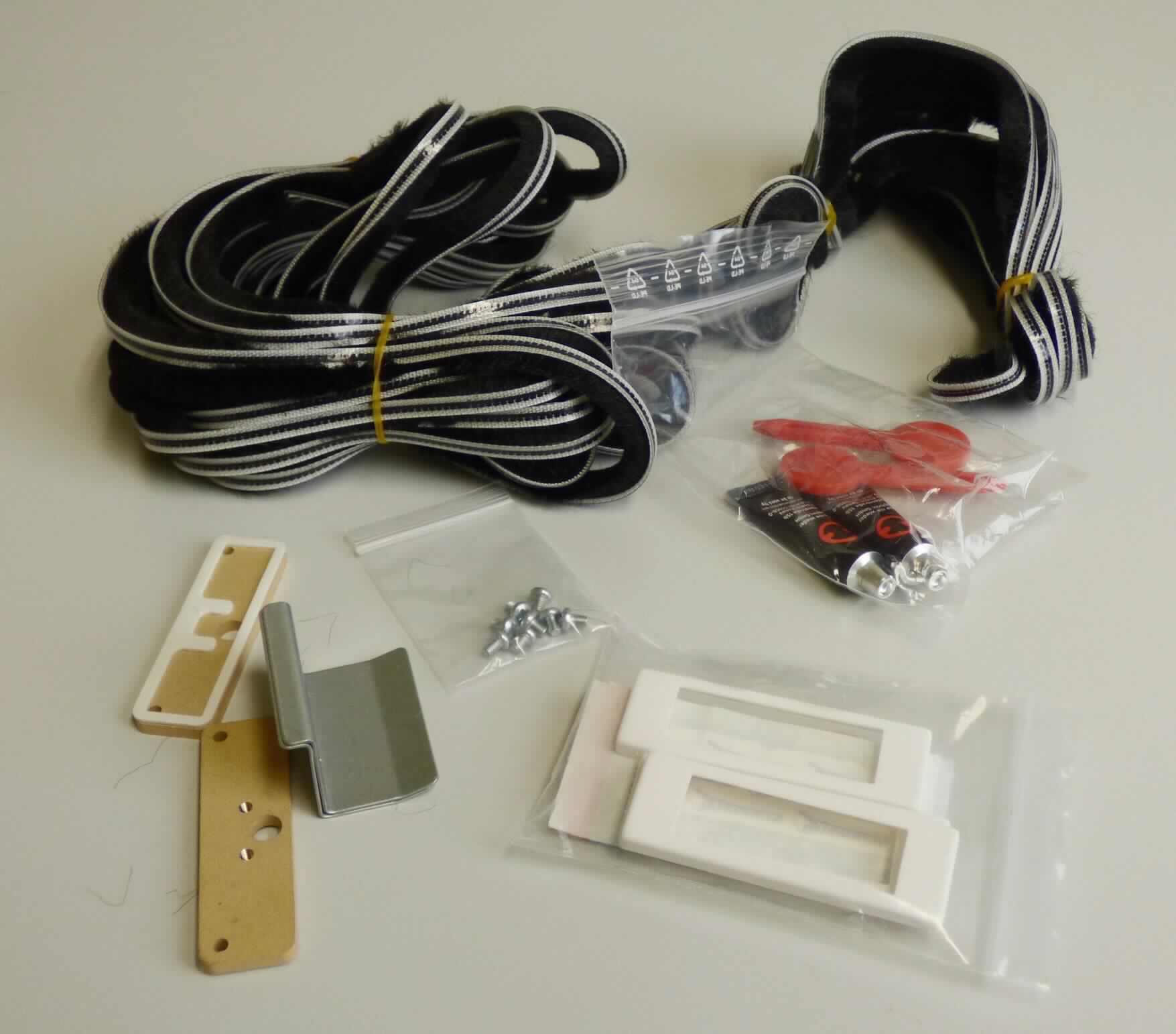 Klebeadapter Set, Foto siehe Anlage,
- Warenzusammenstellung, bestehend aus drei Beschlägen und zwei Gewebebändern sog. "Bürstendichtung",
  gemeinsam mit Montagematerial und einer Montageanleitung in einem bedruckten Pappkarton für den 
  Einzelverkauf aufgemacht und zur Befriedigung eines speziellen Bedarfs zusammengestellt,
- Gewebebänder sog. "Bürstendichtung":
-- als Meterware, mit einer Breite von ca. 0,5 cm und einer Länge von ca. 7 m bzw. 3 m,
-- jeweils:
--- aus einem Band aus Plüschgeweben aus Spinnstoffen (die Schauseite bildend),
--- mit unechten Webkanten,
--- auf der Rückseite wahrnehmbar mit Kunststoff (laut Antrag Polypropylen; kein Zellkunststoff) überzogen,
--- von Hand bei einer Temperatur zwischen 15 und 30 °C auf einen Dorn von 7 mm Durchmesser aufrollbar, 
    ohne rissig zu werden,
- Beschläge:
-- in den Abmessungen (L x B) von ca. 1,7 cm x 5,9 cm,
-- aus augenscheinlich unedlem Metall,
-- mit sog. Abdeckkappen aus Kunststoff, 
-- mit fünf kreisrunden Lochungen, einem Rahmen aus selbstklebenden Kunststoff und Abdeckpapier versehen,
- im Hinblick auf die Verwendung sind die sog. Bürstendichtungen und die Beschläge als gleichbedeutend zu 
  betrachten, im Hinblick auf den Umfang jedoch verleihen die sog. Bürstendichtungen der Warenzusammenstellung
  ihren wesentlichen Charakter.

"Gewebe, mit Kunststoff (Polypropylen) überzogen, anderes als solche der Position 5902, mit Schauseite 
 aus Spinnstoffen"