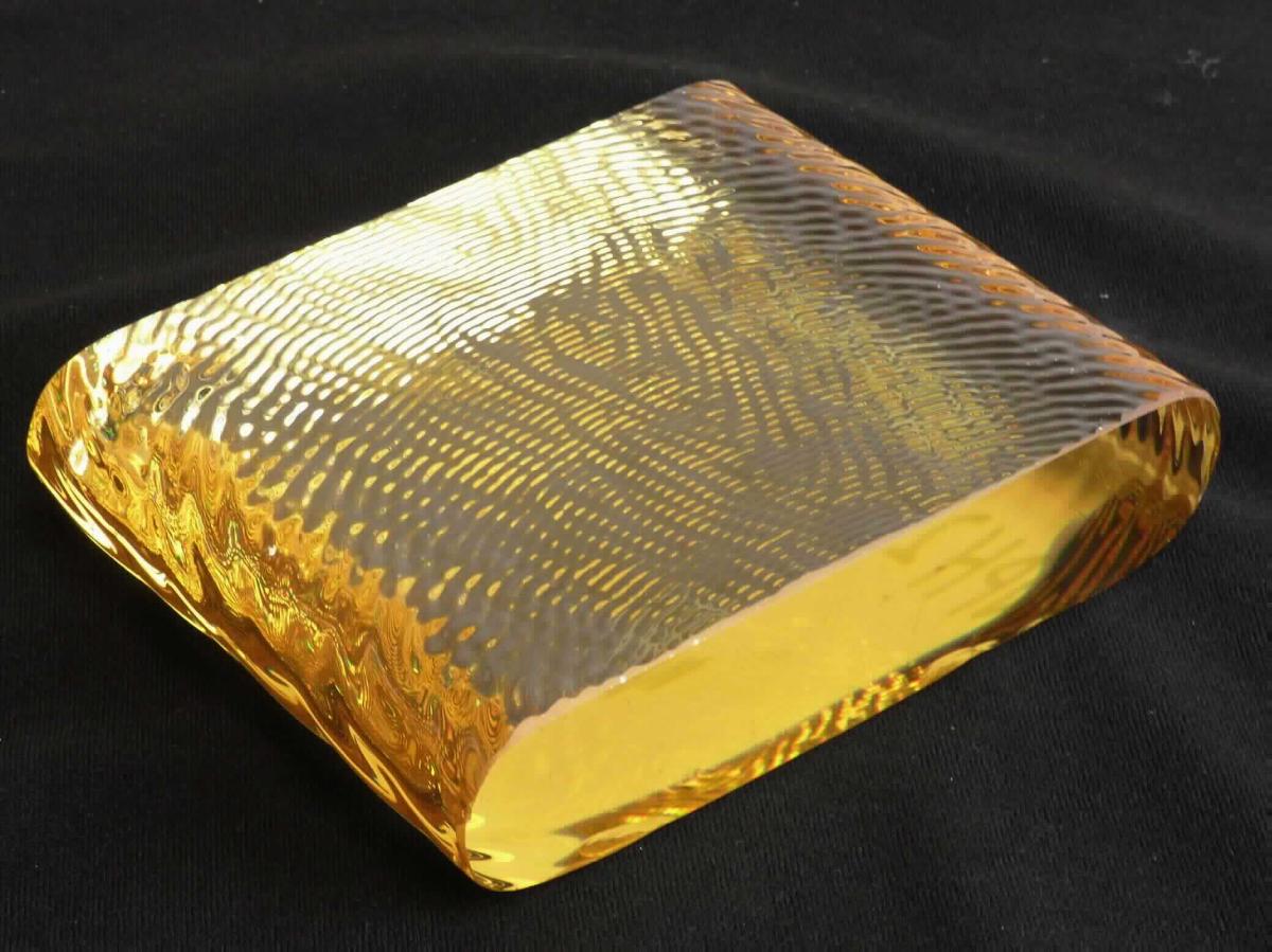 Glasmasse, sog. Barrenglas, Foto siehe Anlage,
- in Form eines laibförmigen Blocks aus Glasmasse mit drei Seiten mit gewellter Oberfläche,
- laut Antrag:
- - aus optischem Glas,
- - an den sog. Mantelseiten feuerpoliert,
- - an den sog. Stirnseiten thermisch gebrochen.

"Glasmasse, optisches Glas"