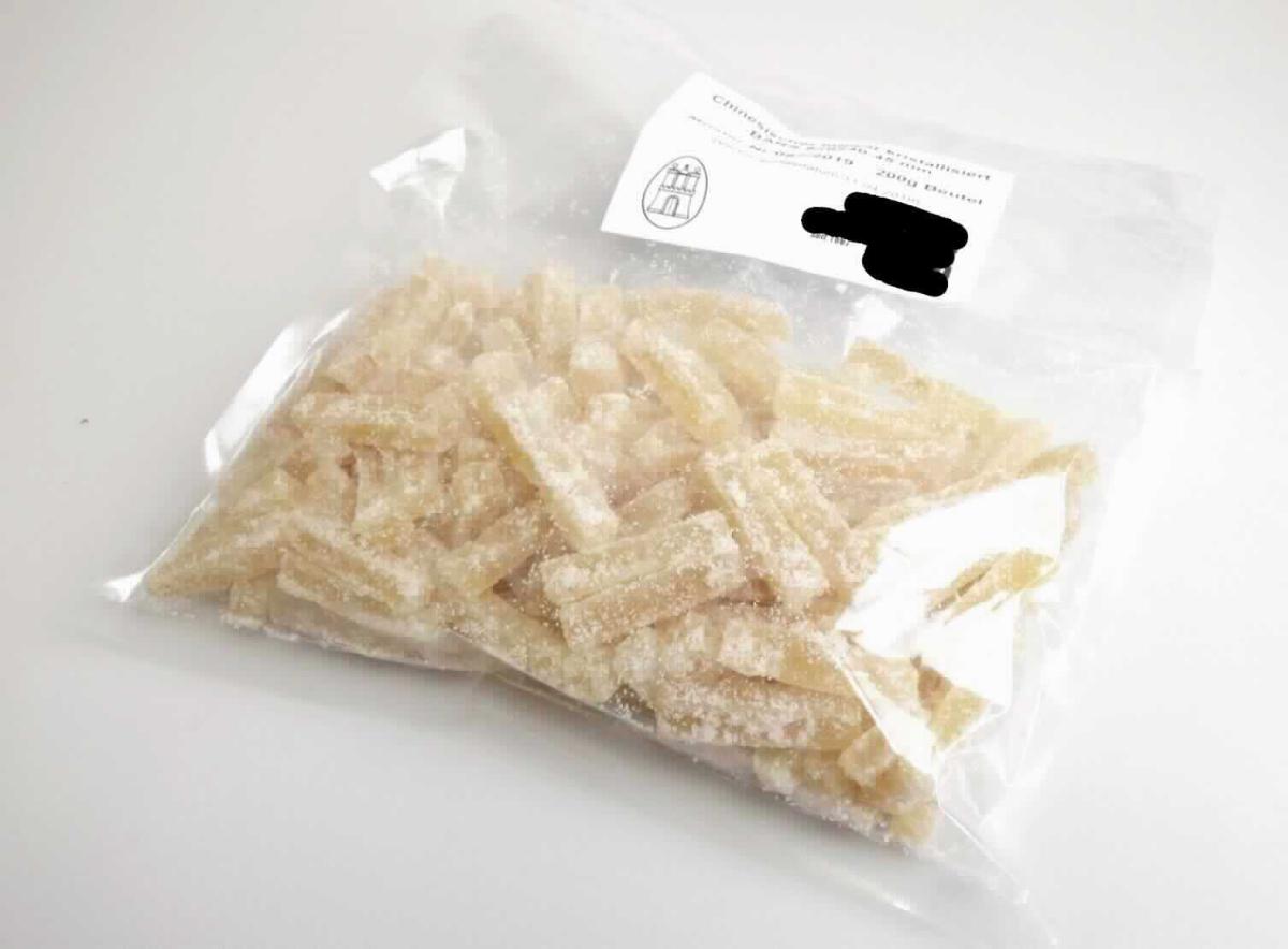 Ingwer, zubereitet.

Antragsangaben (als zutreffend unterstellt): Ingwer in Stücken. Aufmachung: in Packungen in unmittelbaren Umschließungen mit einem Gewicht des Inhalts von mehr als 1 kg. Es wurden vertrauliche Angaben gemacht.

Beschaffenheit des vorgelegten Warenmusters: gelb-beigefarbene, stäbchenförmige, überwiegend mit einer dünnen, anhaftenden Zuckerkristallschicht bedeckte Ingwerstücke (ca. 43 x 8 x 8 mm), süß, scharf und arttypisch schmeckend. 

Zusatz von Alkohol (gemäß Angabe): nicht enthalten. 
Zuckergehalt i. S. der ZAnm 2 a) Abs 1 Kap 20 (gemäß Angabe): mehr als 9 GHT.
Zugesetzter Zucker i. S. der ZAnm 3, 2. Anstrich zu Kap 20 (gemäß Angabe): enthalten.

Der Herstellungsprozess entspricht nicht einem Kandieren im Sinne der Position 2006 der KN.

Früchte, Nüsse und andere genießbare Pflanzenteile, in anderer Weise zubereitet oder haltbar gemacht, auch mit Zusatz von Zucker, anderen Süßmitteln oder Alkohol, anderweit weder genannt noch inbegriffen, andere als in den Unterpositionen 2008 11 bis 2008 97 der Kombinierten Nomenklatur genannt, ohne Zusatz von Alkohol, mit Zusatz von Zucker, in unmittelbaren Umschließungen mit einem Gewicht des Inhalts von mehr als 1 kg, Ingwer.