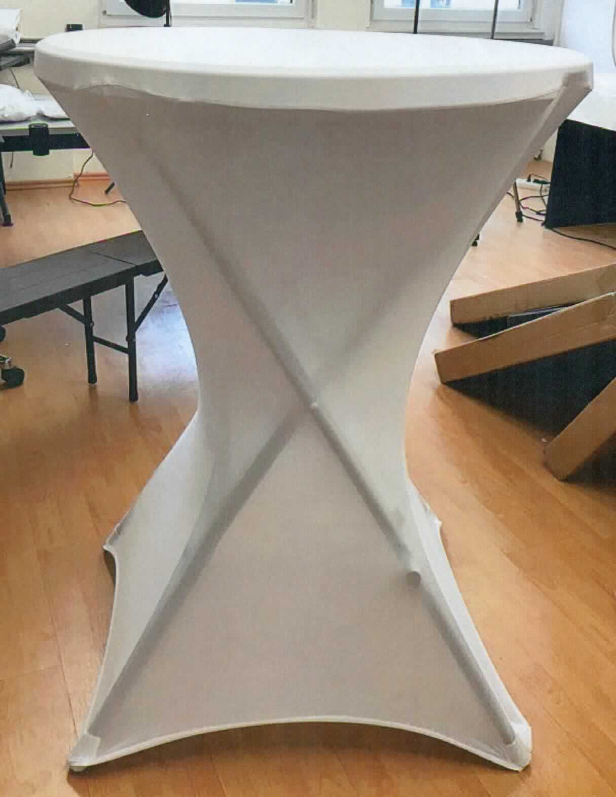 Tischwäsche, sog. Husse für Bartisch, Foto siehe Anlage
- annähernd zylinderförmig, unten offen, mit einem Durchmesser von ca. 80 cm und einer Höhe von ca. 100 cm,
- aus ca. 0,5 mm dicken, einfarbigen Gewirken aus laut Antrag synthetischen Chemiefasern,
- am unteren Rand mit vier eingenähten Zuschnitten aus einem elastischen, gewirkten Band (sog. Fußtaschen), die 
  über die Standfüße gezogen werden und so die Husse am Tisch fixieren, 
- durch Zusammennähen konfektioniert,
- wird üblicherweise gewaschen und kennzeichnet sich nach Material und Verwendungszweck als Tischwäsche.

"Tischwäsche aus Spinnstoffen, aus Gewirken"