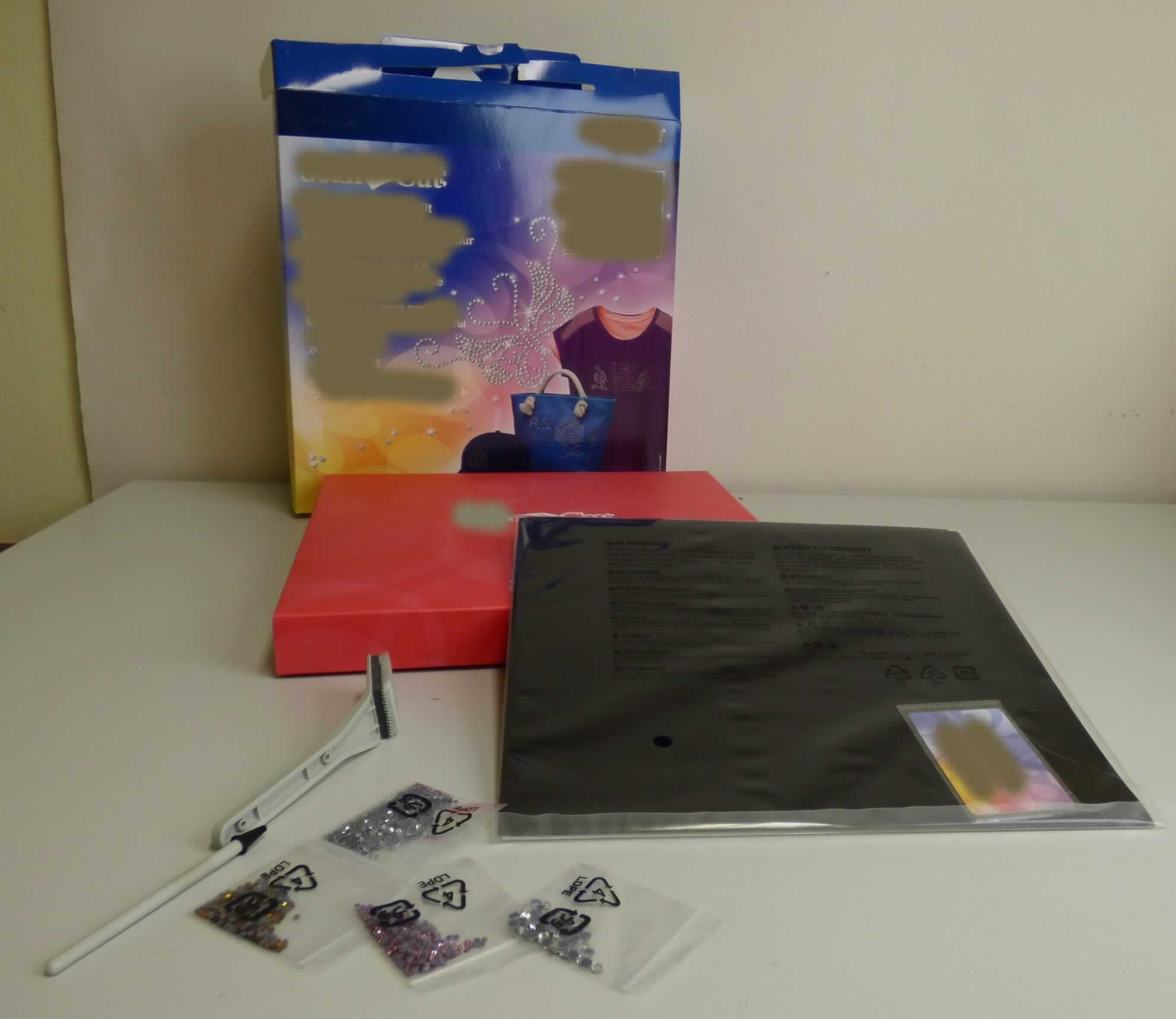 Warenzusammenstellung, bestehend aus Nachahmungen von Edelsteinen, Material zum Aufbringen
der Edelstein-Nachahmungen auf Textilien und Bedienungsanleitungen, sog. Rhinestone Starter Kit, 
Fotos siehe Anlage,
- in Aufmachung für den Einzelverkauf, 
- zur Befriedigung eines speziellen Bedarfs zusammengestellt,
- zur Verwendung mit einer sog. Schneidmaschine (nicht Gegenstand dieser vZTA),
- Nachahmungen von Edelsteinen:
- - in Form von Diamant-Imitationen (Diamantschliff),
- - laut Untersuchungsergebnis aus Glas,
- - mit einem Durchmesser von ca. 2 mm (farblos, orange und rosafarbenen) bzw. 5 mm (farblos),
- - ohne Hinweise auf ein Herstellen durch Schleifen und mechanisches Polieren,
- Material zum Aufbringen der Edelstein-Nachahmungen:
- - zwei schwarze, samtartige, sog. Vorlagenblätter; auf der Unterseite selbstklebend und mit einer
    Schutzfolie versehen,
- - zwei grüne, sog. Transferfolien,
- - eine weiße, sog. Trägerplatte,
- - eine sog. Positionierbürste und ein stiftförmiges, sog. Strasstein-Aufnahmewerkzeug,
- - eine Karte mit einem Aktivierungscode für die Strassstein-Funktion,
- Bedienungsanleitungen,
- im Hinblick auf die Verwendung der Warenzusammenstellung bestimmen die Nachahmungen von
  Edelsteinen deren wesentlichen Charakter.

"Nachahmungen von Edelsteinen (Glaskurzwaren), nicht geschliffen und mechanisch poliert"