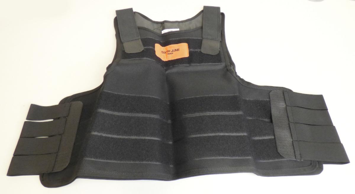 Überwurfähnliches Kleidungsstück, sog. Taktische Weste, in Erwachsenengröße, Foto siehe Anlage,
- in Art eines ärmellosen Überwurfs; aus laut Antrag 100 % Polyester (synthetische Chemiefasern), 
- mit einem Rücken- und einem Vorderteil aus einem ca. 0,5 mm dicken, einfarbigen, einseitig
  (Innenseite) mit geprägtem Kunststoff (kein Zellkunststoff) überzogenen Gewebe der Position 5903,
  die jeweils gefüttert und an den Rändern eingefasst sind,
- mit mehreren gummielastischen, gewebten Bändern, die mit ihren Enden in regelmäßigen Abständen
  und im 90°-Winkel jeweils an ein sog. Hakenband aus Samtgeweben angenäht sind und so
  das Rücken- sowie das Vorderteil an den Seiten und den Schultern miteinander verbinden,
- auf beiden Teilen mit mehreren, großflächig aufgenähten, sog. Flauschbändern aus Schlingengeweben,
- bis über die Taille reichend (max. mögliche Rückenlänge: ca. 62 cm),
- ohne Hinweise auf den Trägerkreis (unisex),
- wird laut Antrag als modisches, einer sog. Taktischen Weste nachempfundenes Kleidungsstück getragen
  und ist nicht als Schutzausrüstung geeignet,
- erfüllt die Merkmale zur Einreihung als Kleidung, somit kein Bekleidungszubehör der Position 6214 und
  kein Schutzüberwurf der Position 6307,
- insbesondere im Hinblick auf das äußere Erscheinungsbild bestimmen die Gewebe der Position 5903
  den Charakter des Kleidungsstücks, u. a. somit keine Kleidung der Position 6211.

"Kleidung (Überwurfähnliches Kleidungsstück) aus Erzeugnissen der Position 5903, aus Geweben, für Frauen"