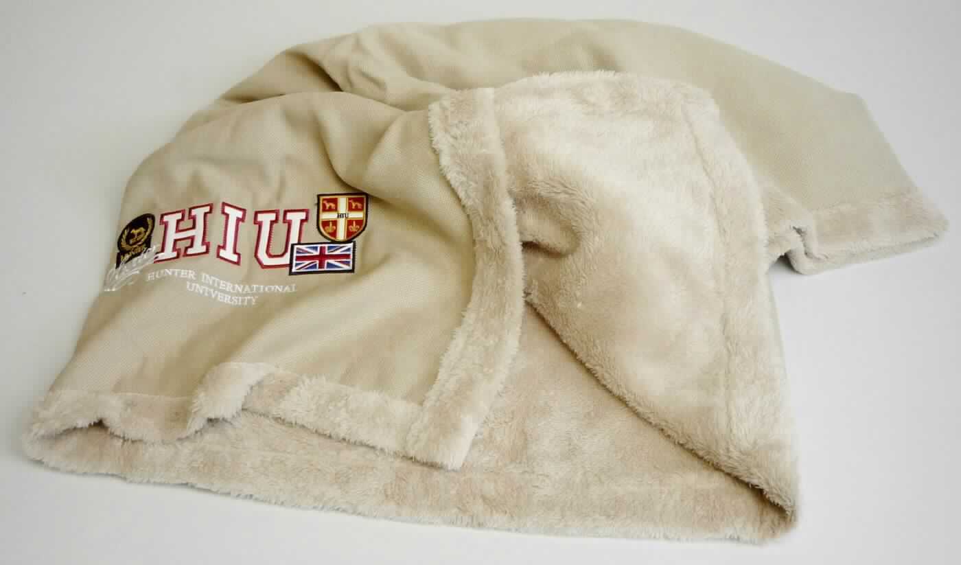 Decke, sog. Hundedecke University M, Art. 61391, Foto siehe Anlage, 
- in einem Polybeutel verpackt, 
- annähernd rechteckig; laut Antrag in den Abmessungen: 120 cm x 78 cm, 
- zweilagig gearbeitet, mit einer Oberlage aus einfarbigen Plüschgewirken und einer Unterlage aus einfarbigen 
  Geweben; auf der Gewebeseite mit einer Stickerei verziert; beide Flächenerzeugnisse aus laut Antrag 100 % 
  Polyester (synthetische Chemiefasern),
- insbesondere im Hinblick auf den Umfang bestimmen die Gewirke gegenüber den Geweben den Charakter 
  der Ware,
- ohne elektrische Heizvorrichtung, 
- durch Zusammennähen konfektioniert, 
- ohne Polsterung oder Füllung; somit keine Ware der Position 9404, 
- soll laut Antrag als Liegedecke für Tiere dienen, 
- nicht zur Ausstattung von Tieren bestimmt, somit keine Ware i. S. d. Position 4201.

"Decke, aus Spinnstoffen, ohne elektrische Heizvorrichtung, aus synthetischen Chemiefasern, aus Gewirken"