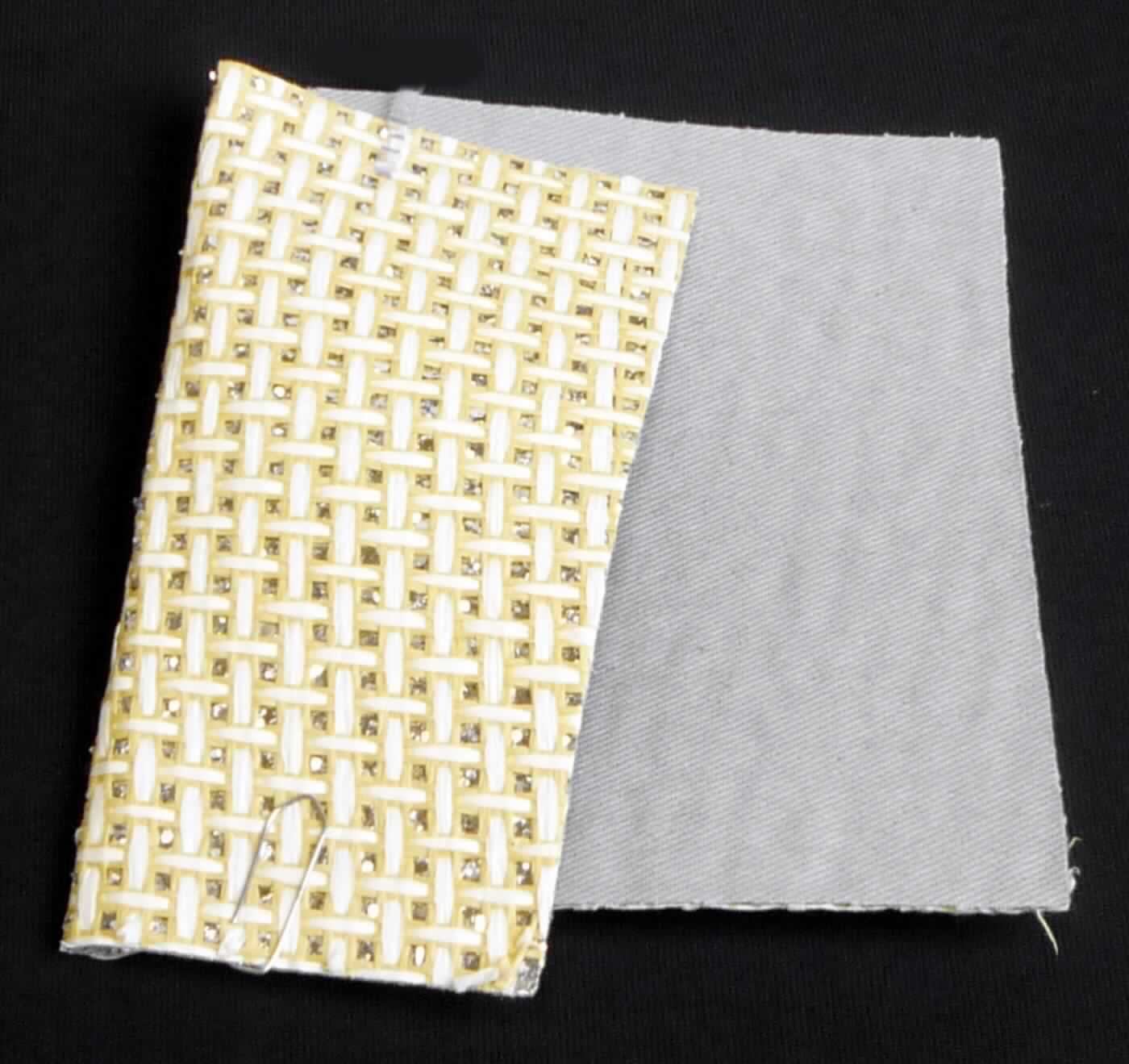 Textillaminat, Foto siehe Anlage,
- als Meterware, laut Antrag mit einer Breite von 140 cm,
- laut Untersuchungsergebnis:
-- aus zwei mit ihrer ganzen Fläche aufeinander liegenden und so miteinander durch Kleben verbundenen Lagen:
--- mit einer Oberlage (Schauseite):
---- aus einem buntgewebten Gewebe in Musterbindung aus gefalteten und gedrehten Papiergarnen der 
     Position 5308,
--- mit einer Unterlage:
---- aus einem einfarbigen Gewebe in Leinwandbindung, 
---- auf der ganzen Oberfläche mit Kleber bestrichen und flächendeckend mit metallisierten Kunststoff-Partikeln
      versehen,
- insbesondere im Hinblick auf die Verwendung verleiht das die Schauseite bildende Gewebe der Ware ihren  
  wesentlichen Charakter.

"Gewebe aus Papiergarnen"