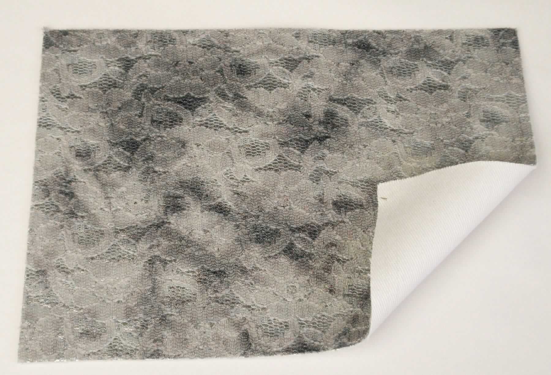 Textillaminat, Foto siehe Anlage,
- als Meterware, laut Antrag mit einer Breite von 130 cm,
- laut Untersuchungsergebnis:
-- aus drei mit ihrer ganzen Fläche aufeinander liegenden und so miteinander durch Kleben verbundenen Lagen: 
--- mit einer Oberlage (Schauseite): 
---- aus einem bedruckten Kettengewirke (sog. Raschelspitze), 
----- mit maschenbildenden Garnen aus synthetischen Chemiefasern (Polyamid),
----- mit ungezwirnten Garnen aus Baumwolle,
----- mit dicken, gezwirnten Garnen aus Baumwolle und künstlichen Chemiefasern (Viskose),
---- mit einem Gesamtanteil an:
----- Baumwolle von ca. 70 GHT,
----- synthetischen Chemiefasern von ca. 25 GHT,
----- künstlichen Chemiefasern von ca. 5 GHT,
---- keine Elastomergarne oder Kautschukfäden enthaltend,
---- kein Samt, Plüsch, Schlingengewirke oder Schlingengestricke,
---- stellt sich nicht als Gewirke im Sinne der Unterpositions-Anmerkung 1 zu Kapitel 60 dar,
--- mit einer Zwischenlage:
---- aus einem Gewirke aus synthetischen Chemiefasern (laut Antrag aus Polyester); einseitig mit metallisierter 
      Farbe versehen,
--- mit einer Unterlage:
---- aus einem einfarbigen Gewebe in Leinwandbindung (laut Antrag aus Baumwolle), 
- im Hinblick auf die Verwendung verleiht das die Schauseite bildende Kettengewirke der Ware ihren wesentlichen
  Charakter.

"Kettengewirke, anderes als solche der Positionen 6001 bis 6004, aus Baumwolle, bedruckt"