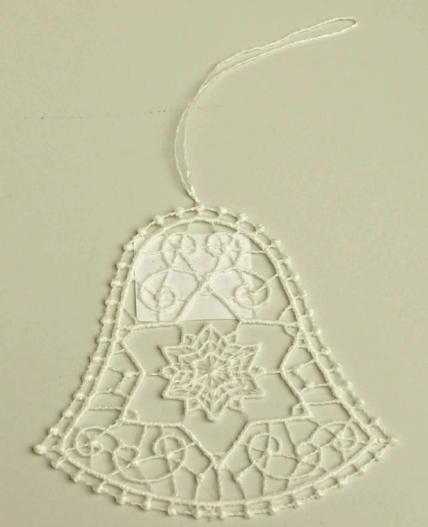 Stickerei, sog. Fensterbild aus Spinnstoff Glocke, Foto siehe Anlage,
- in Form einer Glocke,
- in den Abmessungen von ca. 7 cm x 7 cm,
- laut Untersuchungsergebnis:
-- maschinelle Ätzstickerei als Motiv mit Stickfäden aus laut Antrag 100 % Polyester (synthetische Chemiefasern),
- mit einer aus der Stickerei herausgearbeiteten Aufhängevorrichtung,
- laut Antrag mit einem Wert von mehr als 35 EUR je kg Eigengewicht,
- ohne Hinweise auf Handarbeit,
- stellt sich - unabhängig von der Ausgestaltung - als Winterartikel dar, der vor allem zur Dekoration in der
  Winterzeit verwendet wird (somit keine Ware der Position 9505).

"Ätzstickerei als Motiv, mit einem Wert von mehr als 35 EUR je kg Eigengewicht, nicht handgearbeitet"