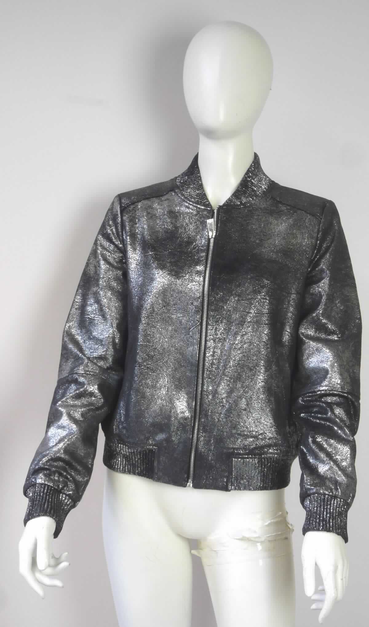 Blouson, sog. Damen Jacke, Größe S, Foto siehe Anlage,
- aus ca. 1 mm dicken, laut Untersuchungsergebnis gerauten, auf der Außenseite musterbildend augenscheinlich 
  mit metallisierter Farbe bedruckten Gewirken (Meterware des Kapitels 60) aus laut Antrag 100 % Polyester 
  (synthetische Chemiefasern), 
- durchgehend gefüttert,
- über die Taille reichend (Rückenlänge: ca. 56 cm),
- mit einem runden Halsausschnitt mit einer gerippt gewirkten Randeinfassung, die hinten einen schmalen 
  Stehkragen bildet, 
- vorn mit einer durchgehenden Öffnung mit Reißverschluss; ohne Hinweise auf den Trägerkreis (unisex), 
- mit langen Ärmeln, die über den unteren Rand des Kleidungsstücks hinausreichen; an den Ärmelenden 
  mit gerippt gewirkten, verengenden Bündchen, 
- mit zwei eingesetzten, offenen Taschen unterhalb der Taille,
- am unteren Rand mit einem angesetzten, gerippt gewirkten, verengenden Bund,
- erfüllt die Merkmale zur Einreihung als Blouson, somit keine Jacke.

"Blouson, aus Gewirken, für Frauen, aus Chemiefasern"