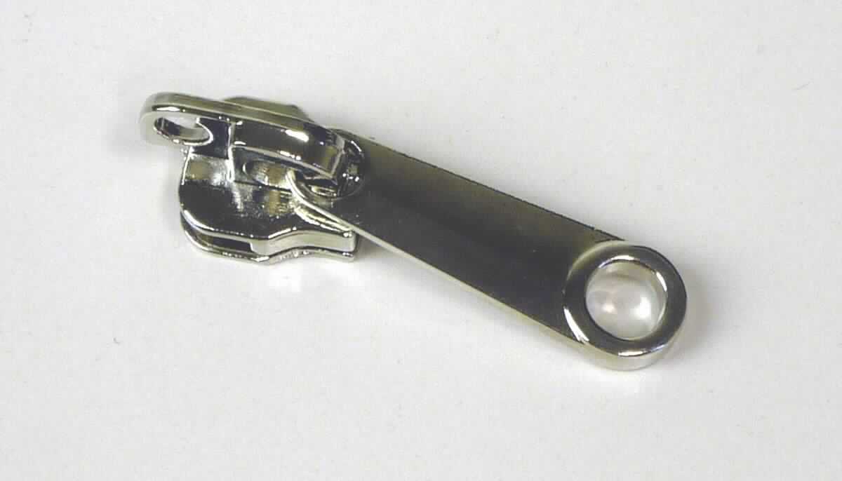 Bei dem sog. "Reißverschlußschlitten aus Nickel" handelt es sich um einen ca. 4 cm langen Schieber für Reißverschlüsse.  

Die Ware ist mit einem Griff ausgestattet, vollständig aus unedlem Metall  hergestellt, mit zwei schienenförmigen Aussparungen versehen und dient dazu, dass die Zähne eines Reißverschlusses ineinander verhakt und wieder gelöst werden können. Auf der Oberseite der Ware befindet sich eine kreisrunde Öffnung (Schloßloch).

Das Erzeugnis ist als erkennbares "Teil eines Reißverschlusses, aus unedlem Metall, Schieber" einzureihen.

Anlage: 1 Abbildung