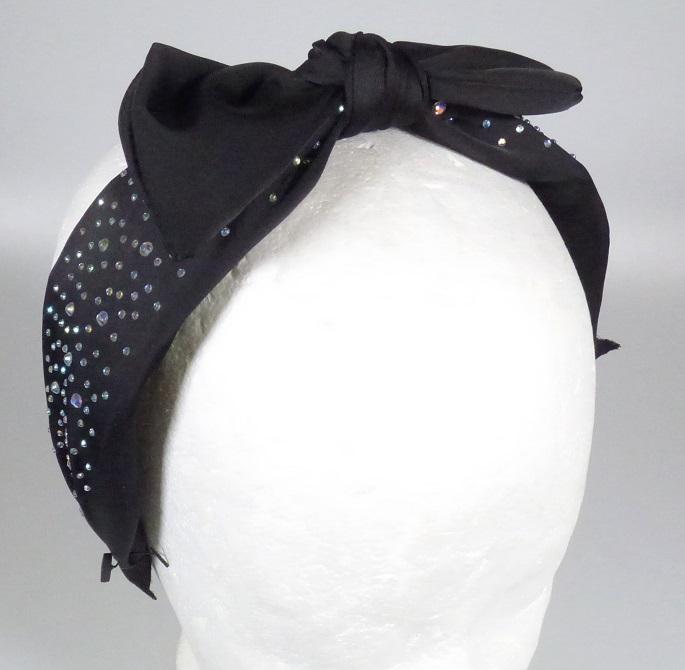 Bei der als "99-SSJM7856 Haarreif mit Strass" bezeichneten Ware handelt es sich um eine aus verschiedenen Stoffen zusammengesetzte Ware, bestehend aus einem ca. 4 cm breiten, gebogenen, der Kopfform angepassten, an den Enden offenen Reif aus Metall mit einem Überzug aus Vliesstoff und einer darüber befindlichen äußeren Lage aus schwarzen Spinnstoffen.
Der Reif ist zusätzlich auf der Oberseite mit einer aufgesetzten Schleife aus Spinnstoff und vielen unterschiedlich großen Strass-Steinchen aus Kunststoff bestückt.

Der Haarreif wird zum Zusammenhalten des Haares und zugleich als Schmuck verwendet.

Bei dem aus unterschiedlichen Stoffen bestehendem Haarreif wird der stoffliche Charakter der Ware vom Metall (charakterverleihend in Hinblick auf die Verwendung) und dem Spinnstoff (charakterverleihend im Hinblick auf das äußere Erscheinungsbild) bestimmt. 

Die Ware ist als "haarspangenähnliche Ware, aus anderen Stoffen als Hartkautschuk oder Kunststoff" einzureihen.