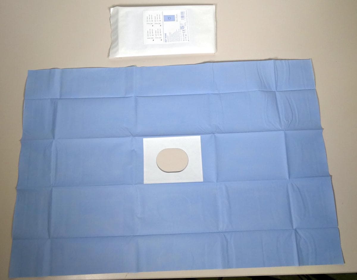 Abdecktuch

Bei der vorgelegten Ware handelt es sich um ein 2-lagiges, blaues Abdecktuch mit Loch. Die obere Schicht besteht aus saugfähigem Polypropylen-Vlies. Die untere Schicht besteht aus einer feuchtigkeitsundurchlässigen Polyethylen-Folie als zuverlässigem Barriereschutz. Das Loch hat die Größe von 6 cm x 8 cm und entlang der Öffnung befindet sich eine Klebefläche. Das Abdecktuch ist einzeln steril verpackt. Mehrere Abdecktücher sind in einem bunt bedruckten Faltkarton verpackt und für den Einzelverkauf zu medizinischen Zwecken aufgemacht. 
Laut Produktbeschreibung dient das Abdecktuch zur sterilen Abgrenzung des Operationsfeldes. Leicht abziehbare Kontrollaufkleber auf der Verpackung erleichtern die OP-Dokumentation.

Die Ware ist als andere Ware mit Klebeschicht in die Unterposition 3005 1000 der Kombinierten Nomenklatur einzureihen