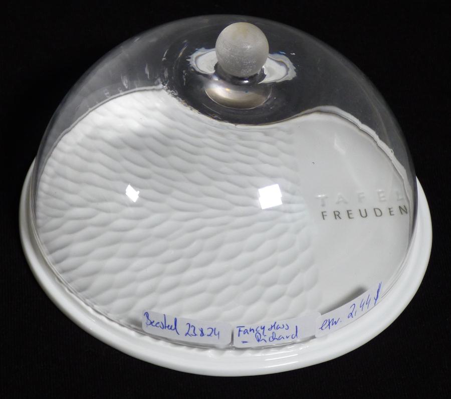 Glasware zur Verwendung bei Tisch oder in der Küche, Foto siehe Anlage,
- in Form einer Abdeckhaube mit einer tellerförmigen Unterlage,
- aus einer halbkugelförmigen Haube (Glocke) mit einem kugelförmigen Griff,
- - aus klarsichtigem, gewöhnlichem Glas,
- - - mit manueller Glasentnahme (laut Antrag),
- - mit einem Durchmesser von ca. 14 cm und einer Höhe von ca. 8 cm,
- mit einer tellerförmigen Unterlage aus laut Antrag Porzellan,
- - an der Oberseite glasiert und mit unregelmäßigen Vertiefungen sowie einem Schriftzug verziert,
- - mit einem Durchmesser von ca. 15 cm und einer Höhe von ca. 0,5 cm,
- dient dem Aufbewahren und Servieren von Lebensmitteln,
- das Glas und das Porzellan sind im Hinblick auf ihre Bedeutung in Bezug auf die Verwendung
  gleichbedeutend; somit verleiht keiner der beiden Stoffe der zusammengesetzten Ware den
  wesentlichen Charakter und diese ist daher der von den gleichermaßen in Betracht kommenden
  Positionen (6911 / 7013) in der Nomenklatur zuletzt genannten Position zuzuweisen.

"Glasware zur Verwendung bei Tisch oder in der Küche, kein Trinkglas, aus gewöhnlichem Glas,
  handgefertigt (manuelle Glasentnahme)"