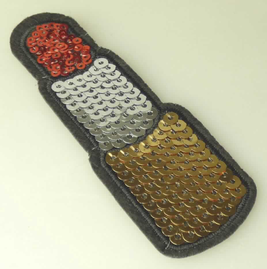 Applikationsstickerei, sog. Applikation "Lipstick" mit Pailletten, Art. 1450-23, Foto siehe Anlage,
- als Motiv, in Form eines Lippenstiftes, in den Abmessungen: ca. 10 cm x 3,5 cm,
- mit einem Stickgrund aus einem Vliesstoff aus synthetischen Chemiefasern (laut Antrag aus Polyester),
- auf diesem Grund sind mittels Stickfäden Pailletten aufgestickt,
- auf der Rückseite mit klarsichtigem Kleber versehen,
- keine Ätzstickerei oder Stickerei mit herausgeschnittenem Grund,
- laut Antrag mit einem Wert von 95,59 EUR je kg Eigengewicht,
- ohne Hinweise auf Handarbeit.

"Stickerei als Motiv, andere als Ätzstickereien und Stickereien mit herausgeschnittenem Grund, aus Chemiefasern, 
 mit einem Wert von mehr als 17,50 EUR je kg Eigengewicht, nicht handgearbeitet"