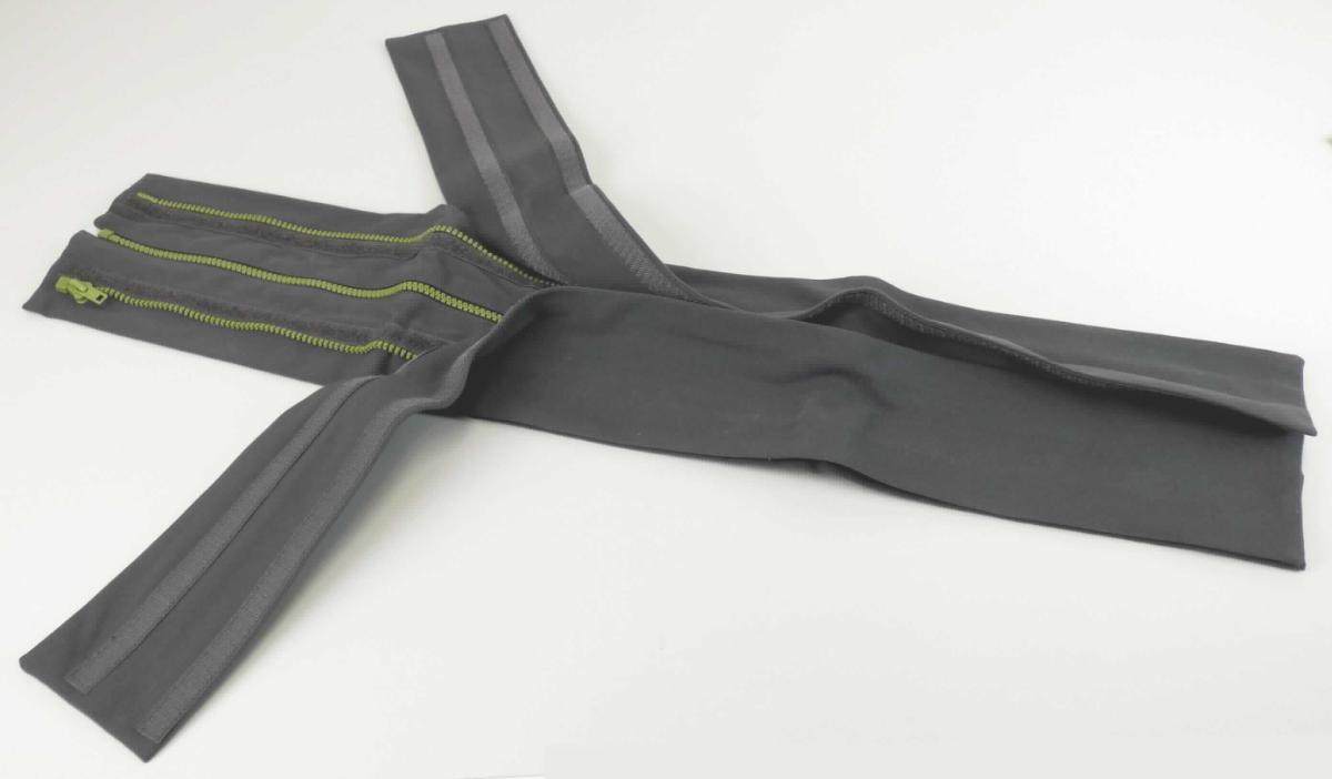 Das Erzeugnis, sog. "Verbreiterung" besteht im Wesentlichen aus zwei doppellagig genähten, ca. 6,5 cm breiten sowie ca. 71 cm langen Stoffbändern, die an der inneren Längsseite jeweils mit einem textilen Streifen mit Kunststoffzähnchen sowie Stops versehen sind. Die zwei gegenüberliegenden Zähnchenreihen sind mittels eines Schiebers ineinander verhakt.
Auf die Bänder ist mittig jeweils ein schmaler, textiler, mit Klett versehener Streifen mit Kunststoffzähnchen an der nach außen zeigenden Längsseite mit Stops aufgenäht. Einer der beiden Streifen ist mit einem Endstück (Bottom Stop) sowie einem Schieber versehen.
Auf den Klettstreifen ist mittels Klettverschluss abnehmbar jeweils eine sog. Blende in Form eines ca. 8,8 cm breiten und ca. 71 cm langen, doppellagig genähten Stoffbandes fixiert.

Das Erzeugnis stellt eine aus verschiedenen Bestandteilen zusammengesetzte Ware dar, deren Charakter aufgrund der Bedeutung für die Verwendung sowie des Gesamteindrucks durch den Reißverschluss-Bestandteil bestimmt wird.

Die mit einem Pappetikett umwickelte Ware dient zum Verbreitern von Jacken während einer Schwangerschaft. Sie soll bereits erweiterte Jacken zusätzlich erweitern und wird links sowie rechts mit der Erweiterung (Kumja) verbunden und an den Reißverschlussadapter gezippt, der wiederum an der Jacke fixiert ist.

Die Ware ist als "Reißverschluss mit Zähnen aus Kunststoff" einzureihen.

Anlage: 1 Abbildung