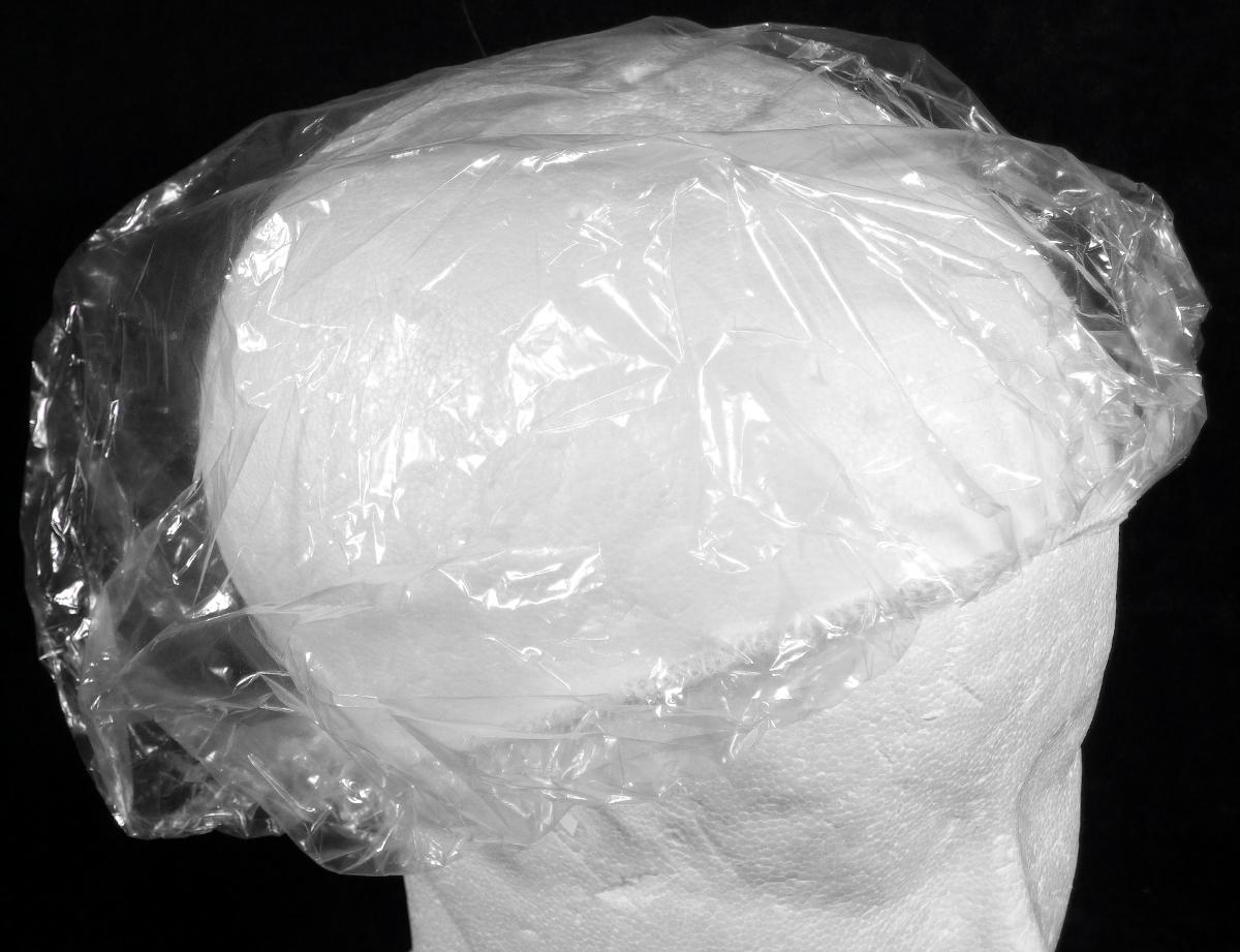 Kopfbedeckung (Duschhaube), sog. PE-Duschhaube transparent, Foto siehe Anlage,
- aus einer klarsichtigen Kunststofffolie gearbeitet,
- der Kopfform annähernd angepasst hergestellt,
- am Rand mit einem elastischen Gummizug verengt und mit einem Faden aus Spinnstoffen gesäumt,
- zur Verwendung als Schutzhaube beim Duschen zum Bedecken des gesamten Haares,
- einzeln in einem kleinen Beutel verpackt.

"Andere Kopfbedeckung (Duschhaube), aus Kunststoff"