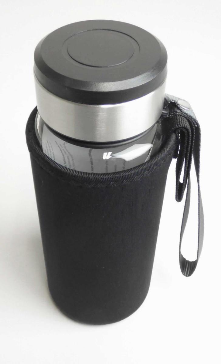 Warenzusammenstellung, bestehend aus einer zusammengesetzten Ware und einer anderen Ware aus Spinnstoffen (Art. 332-00.001), sog. Glastrinkflasche, Foto siehe Anlage,
- in Aufmachung für den Einzelverkauf in einem klarsichtigen Polybeutel mit Anleitung in einem Karton verpackt,
- zur Befriedigung eines speziellen Bedarfs zusammengestellt (dient laut Antrag u. a. der Zubereitung von Tee
  sowie dem Transport und der Aufbewahrung von kalten und warmen Getränken),
- zusammengesetzte Ware, bestehend aus:
- - einem zylinderförmigen Behältnis:
- - - aus nicht gefärbtem, klarsichtigen Glas,
- - - mit einem Durchmesser bis zu 7,5 cm und einer Höhe von ca. 20 cm,
- - - am oberen, offenen Rand leicht verjüngt; mit einem Schraubgewinde,
- - - mit einem Nenninhalt von 0,8 Litern,
- - - mit einer Handtrageschlaufe aus Geweben, befestigt an einem Ring aus formgepresstem Kunststoff,
- - einem Verschlussdeckel:
- - - aus unedlem Metall (laut Antrag Edelstahl) und Kunststoffen,
- - - mit einem Gewinde und einer Dichtung,
- - - wird auf den Flaschenhals aufgeschraubt,
- - einem Sieb (Teefilter):
- - - aus unedlem Metall,
- - - mit einem umlegbaren Handgriff,
- - - wird in den Flaschenhals eingesetzt,
- - der Behälter aus Glas bestimmt nach dem Umfang den wesentlichen Charakter der zusammengesetzten Ware,
- andere konfektionierte Spinnstoffware:
- - in Form eines am oberen Ende offenen Überzugs aus Neopren mit einer Schlaufe aus Geweben zum Tragen
    oder Aufhängen,
- - soll als Isolierung und zum Schutz der Glasflasche dienen,
- der Behälter aus Glas bestimmt nach dem Umfang und seiner Bedeutung in Bezug auf die Verwendung 
  den wesentlichen Charakter der Warenzusammenstellung.

"Flasche aus Glas, zu Transport- oder Verpackungszwecken, nicht aus Glasröhren hergestellt, aus nicht 
 gefärbtem Glas, mit einem Nenninhalt von 0,8 l, für Nahrungsmittel und Getränke"