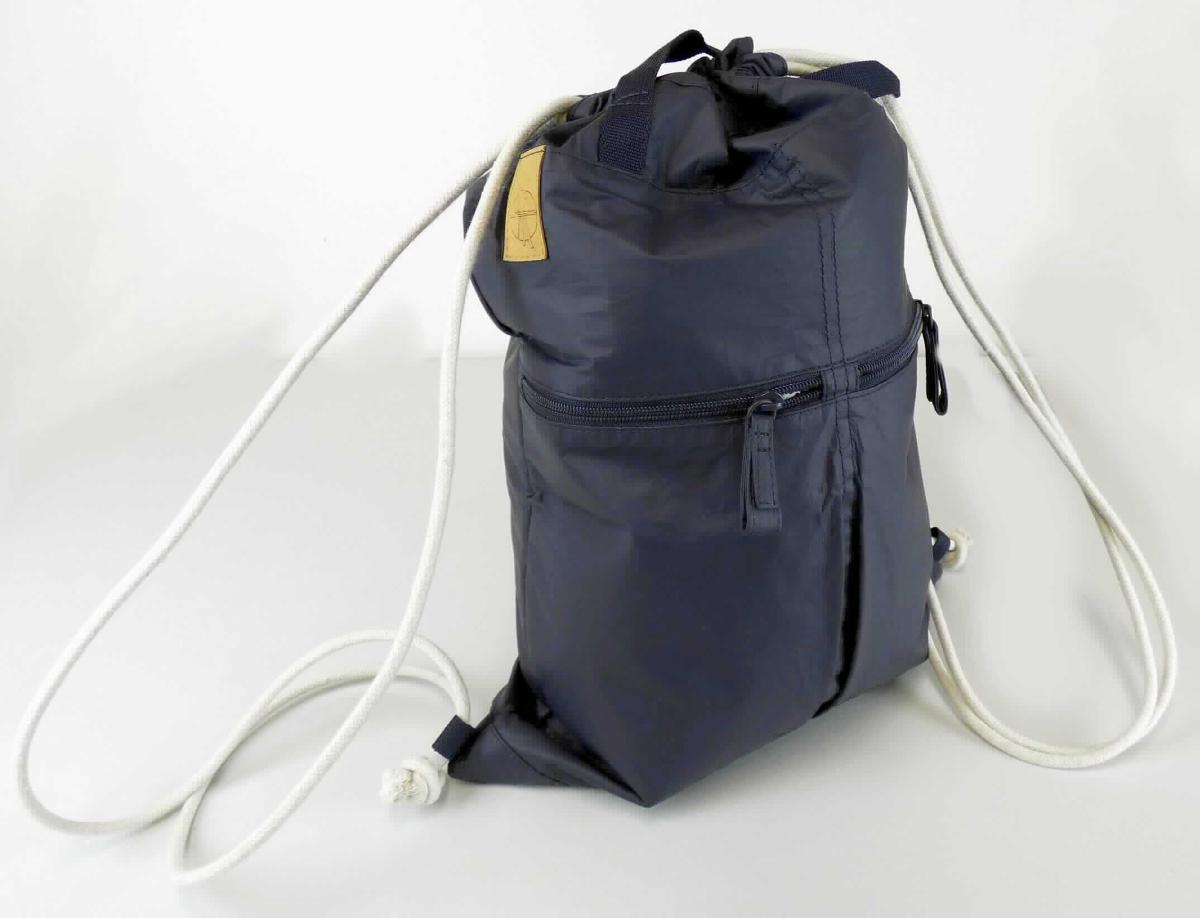 Rucksack, sog. Turnbeutel, Artikel 1103017401, Foto siehe Anlage, 
- mit einer Außenseite aus geprägten Kunststofffolien (laut Antrag aus Polyurethan) auf einer Unterlage 
  aus Spinnstoffen (laut Antrag Tyvek aus Polyethylen), 
- mit zwei Handtragegriffen,
- auf der Vorderseite mit zwei eingesetzten Reißverschlussfächern, auf der Rückseite mit einem
  eingesetzten Reißverschlussfach,
- innen gefüttert und mit einem Reißverschlussfach ausgestattet,
- am oberen Rand mit einer Zugkordel zu verengen, die an beiden Seiten bis zu den unteren Ecken
  des Beutels durch Schlaufen geführt wird,
- in den Abmessungen: ca. 35 cm (Breite) x 49 cm (Höhe).

"Rucksack, mit Außenseite aus Kunststofffolien"