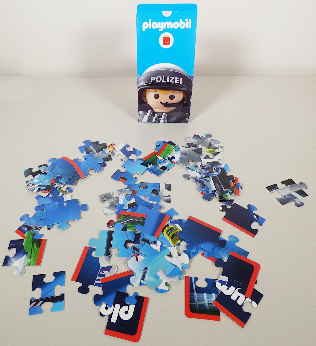 Bei dem vorliegenden und als "Mc Donald's - Playmobil 2021 - Motiv Polizei Wendepuzzle" bezeichneten Erzeugnis handelt es sich um ein Puzzle als Warenzusammenstellung in Aufmachung für den Einzelverkauf, bestehend aus
- einem Puzzle,
- - aus 30 Puzzleteilen aus Pappe,
- - die Teile sind mit Ausformungen und Einbuchtungen versehen, so dass sie sich zusammensetzen lassen,
- - zusammengesetzt in den Abmessungen von ca. 40 x 30 cm,
- - auf der Vorderseite mit einem fliegenden Spielzeug-Polizeihelikopter und auf der Rückseite mit einem Spielzeug-Polizeieinsatzwagen bedruckt, 
- mit einer ca. 29,5 x 21 cm großen Vorlage aus Papier, die auf der Schauseite mit beiden zusammengesetzten Motiven bedruckt ist und auf der Rückseite nochmal beide Motive als Ausmalvorlage aufweist,
- dient der spielerischen Unterhaltung von Kindern,
- gemeinsam in einem bedruckten Pappkarton verpackt.

Im Hinblick auf den Umfang und die Bedeutung für die Verwendung bestimmt das Puzzle den Charakter der Warenzusammenstellung.

Derartige Erzeugnisse werden zolltarifrechtlich als "Puzzle, nicht aus Holz" eingereiht.