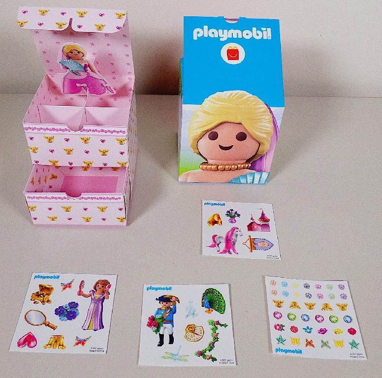 Ware aus Pappe in Form einer Schachtel, "Mc Donald´s - Playmobil - 2021 - Motiv Schmuckkästchen"
- aus farbig bedruckter Pappe hergestellt
- in den Abmessungen von ca. 9,5 x 9,5 x 9,5 cm
- mit einer herausziehbaren Schublade
- an der Oberseite mit einem aufklappbaren Deckel und vierfach unterteilten Fach sowie einer
   eingeklebten Abbildung einer Playmobilfigur, die sich beim Öffnen des Deckels aufstellt
- dient der Aufbewahrung von kleinen Gegenständen
- gemeinsam mit vier Bogen Aufklebern in einer bunt bedruckten Pappschachtel für den Einzelverkauf aufgemacht.

Da Schmuckkästchen und Aufkleber nicht zur Befriedigung eines speziellen Bedarfs oder zur Ausübung einer bestimmten Tätigkeit zusammengestellt worden sind, scheidet eine Einreihung als Warenzusammenstellung im Sinne der Allgemeinen Vorschrift  3 b) aus und die Waren sind getrennt einzureihen (siehe vZTA DEBTI-25893/21-2 für die Aufkleber).

Die Ware ist zolltarifrechtlich als "Pappware von der in Büros, Geschäften und dergleichen verwendeten Art" einzureihen.