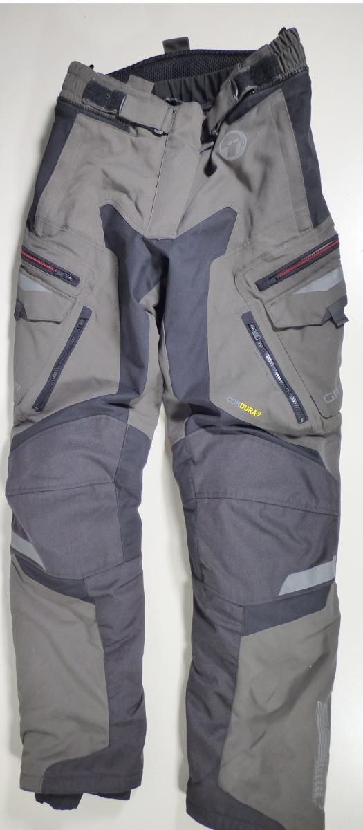 Zwei miteinander verbundene Kleidungsstücke, bestehend aus einer langen Hose aus Geweben der Kapitel 54/55 (Außenteil) und einer langen Hose aus Geweben der Position 5903 (Innenteil), sog. BÜSE Gravel XR Damen Hose, Größe 38, Foto siehe Anlage,
- in einem Polybeutel verpackt,
- beide Teile sind durch einen Reißverschluss und Druckknopflaschen miteinander verbunden,
  können aber auch separat getragen werden,
- lange Hose aus Geweben der Kapitel 54/55:
-- aus verschiedenen ca. 0,6 mm dicken, einfarbigen Geweben aus laut Antrag 100 % synthe-
   tischen Chemiefasern,
-- durchgehend gefüttert,
-- in der Taille abschließend; mit einem angesetzten, teilweise elastisch verengten Bund mit einem 
   Verbindungsreißverschluss zur Befestigung an einem Oberteil; mit zwei Klettverschlussriegeln 
   weitenregulierbar,
-- vorn mit einem erweiternden Einsatz, der mit einem Reißverschluss und einer Patte mit einem
   Haken-  und Druckknopfverschluss von rechts über links zu verengen ist,
-- ohne Öffnung und ohne Verschluss; ohne Hinweise auf den Trägerkreis (unisex), 
-- mit verschiedenen ein- und aufgesetzten Taschen,
-- mit mehreren mit Gewirken unterlegten Belüftungsschlitzen mit Reißverschluss ausgestattet,
-- laut Antrag im Bereich der Hüfte und der Knie mit herausnehmbaren Protektoren, 
-- mit reflektierenden Aufdrucken und im Gesäßbereich mit sog. Antirutschmaterial versehen,
-- mit knöchellangen Hosenbeinen; an den Beinabschlüssen mit Klettverschlussriegeln zu verengen
   sowie mit ca. 31 cm hochreichenden Reißverschlüssen mit erweiternden Einsätzen ausgestattet,
-- keine Arbeits- und Berufskleidung.

"Lange Hose, aus Geweben, für Frauen, aus synthetischen Chemiefasern, keine Arbeits- und 
 Berufskleidung, nicht nach dem Batik-Verfahren handbedruckt"