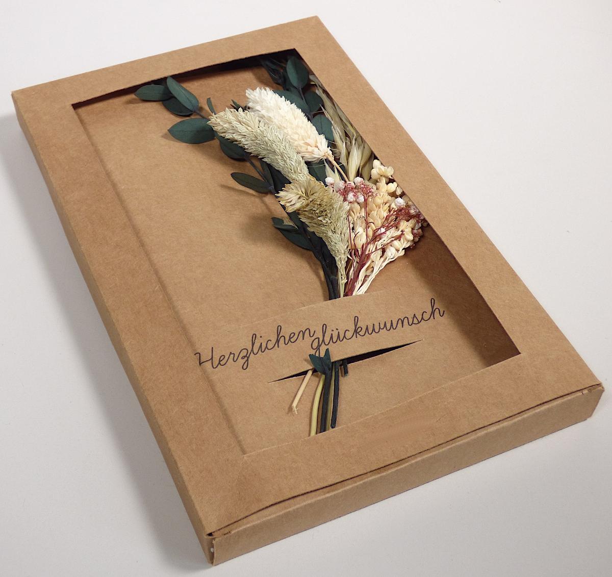 Es handelt sich um eine Klappkarte aus brauner Pappe (Format gefaltet etwa 14,0 cm x 21,0 cm), die vorderseitig mit dem Schriftzug "Herzlichen Glückwunsch" bedruckt ist. In die Vorderseite ist eine etwa 6,0 cm x 2,5 cm große Lasche eingearbeitet, in die ein Trockenblumenstrauß mit echten Blumen (Laut Angaben des Antragstsellers: Gypsophila paniculata L., Setaria viridis (L.) Beauv., Staticesinuate L, Chrysanthemum indicum L.), eingesteckt ist. Die Glückwunschkarte mit den Trockenblumen ist in einer Pappschachtel mit Sichtfenster verpackt.

Abbildung siehe Anlage.

Derartige Waren gehören als "Glückwunschkarten, auch mit Verzierungen aller Art" zur Codenummer 4909 00 00 00 0 des Zolltarifs.