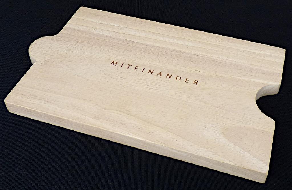 Schneidebrett (Abbildung siehe Anlage)
- Brett in rechteckiger Form aus massivem Kautschukbaum Holz (Rubberwood,
  Hevea-brasiliensis, lt. Antragsteller), glatt geschliffen, auf einer Schmalseite
  mit einer halbkreisförmigen Einbuchtung, an der gegenüberliegenden
  Schmalseite mit einer halbkreisförmigen Ausbuchtung, mittig 
  mit einem eingravierten Schriftzug "MITEINANDER" versehen,
  in den Abmessungen: ca. 23 x 15 x 1,5 cm, 
- zur Verwendung bei Tisch oder in der Küche. 

"Holzware zur Verwendung bei Tisch oder in der Küche, nicht aus Bambus, aus tropischem Holz,
 nicht aus tropischem Holz im Sinne der zusätzlichen Anmerkung 2 zu Kap 44 - Schneidebrett"
