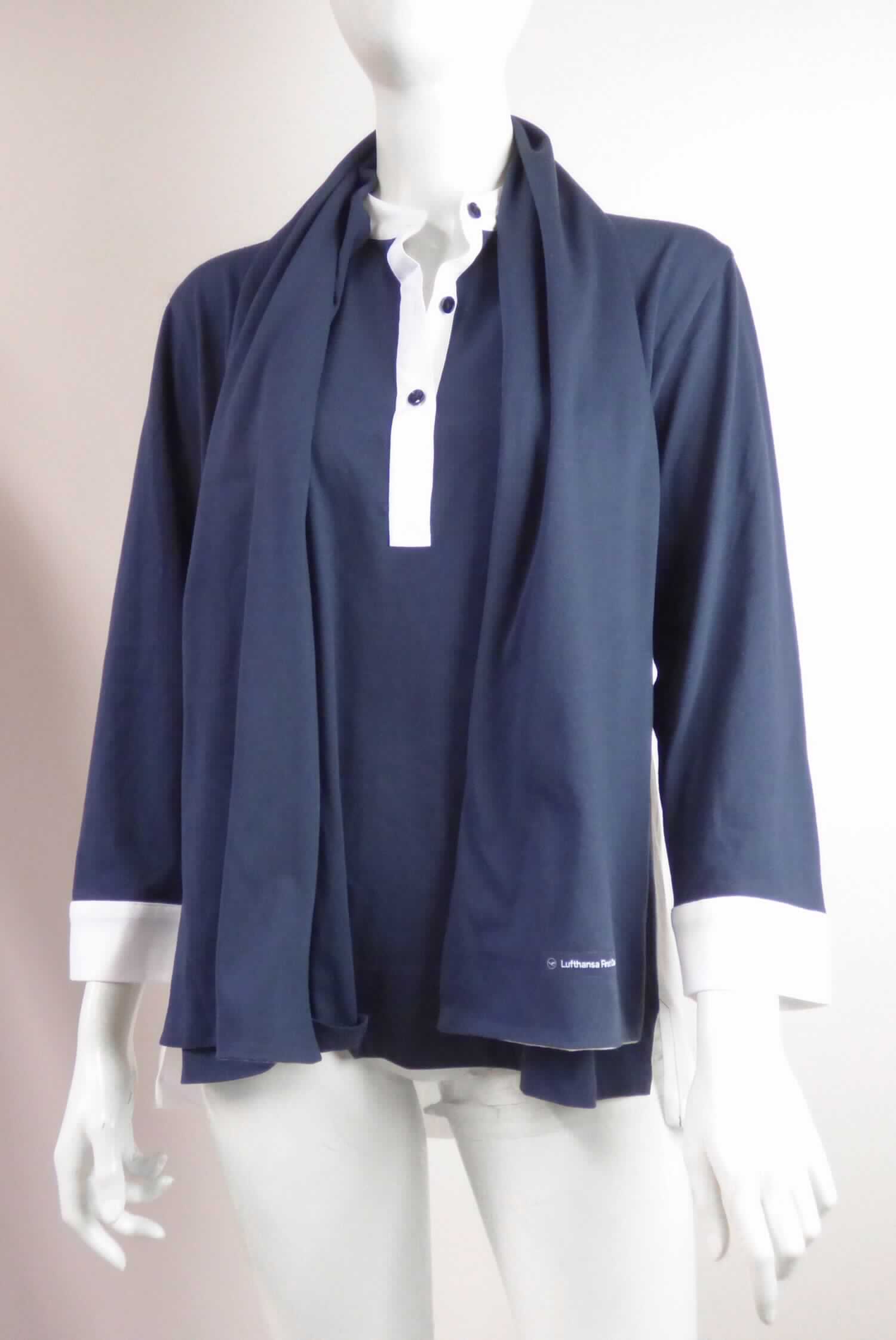 Hemdbluse und Schal, Pyjama Top Damen, Art.-Nr.: TW-S-36300975-Form 8479, Foto siehe Anlage,
- stellt sich als Warenzusammenstellung dar,
- gemeinsam in einem Polybeutel für den Einzelverkauf aufgemacht und zur Befriedigung eines speziellen Bedarfs 
  zusammengestellt,
- aus verschiedenen, ca. 0,5 mm dicken, einfarbigen (blau und weiß) Gewirken aus laut Antrag 60 % Baumwolle 
  und 40% Polyester (synthetische Chemiefasern), mit durchschnittlich mehr als 10 Maschen in jeder Richtung je 
  linearen Zentimeter,
- Hemdbluse:
-- über die Taille reichend (Rückenlänge: ca. 72 cm),
-- mit einem kurzen Stehkragen aus kontrastfarbenen Geweben,
-- vorn mit einer nicht durchgehenden Öffnung mit Knopfverschluss von rechts auf links (Frauenkleidung), mit einer 
   Knopfleiste aus kontrastfarbenen Geweben,
-- mit langen Ärmeln, an den Ärmelenden mit kontrastfarbenen angesetzten Bündchen,
-- den Hemden für Männer entsprechend zugeschnitten,
-- am unteren Rand durch Umschlagen und Festnähen gesäumt,
-- stellt sich als einzelnes Kleidungsstück zum Bedecken des Oberkörpers dar, somit kein Schlafanzug,
- Schal:
-- in den Abmessungen: ca. 146 cm lang und ca. 23 cm breit,
-- zweilagig gearbeitet,
- nach dem Umfang, dem Wert und der Bedeutung in Bezug auf die Verwendung bestimmt die Hemdbluse den 
  Charakter der Warenzusammenstellung.

"Hemdbluse, aus Gewirken, für Frauen, aus Baumwolle"