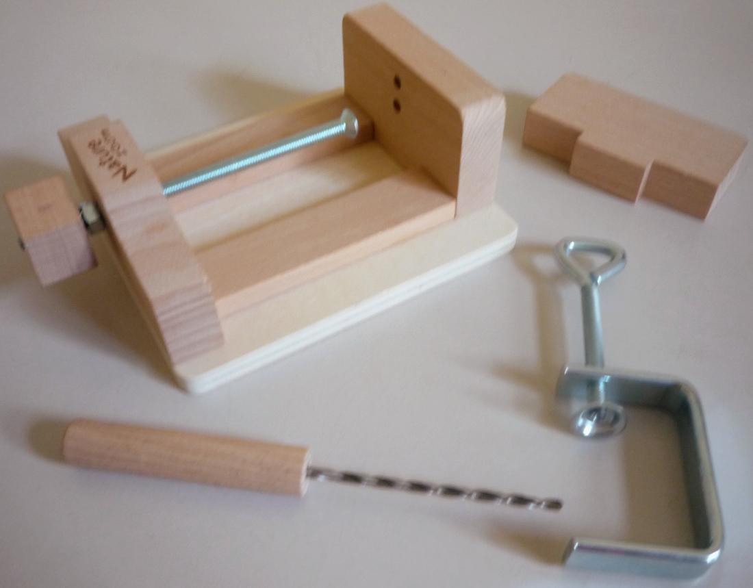 "Multi-Schraubstock aus Holz"
Warenzusammenstellung in Aufmachung für den Einzelverkauf, bestehend aus

- einem noch nicht zusammengesetzten Schraubstock (Pos. 8205)

- - aus einer Grundplatte, einer festen Spannbacke und einer lose eingelegten
    Spannbacke, jeweils aus Holz, die mittels einer in einer fest angebrachten
    Halterung aus Holz mit eingesetztem Innengewinde geführten Geweindespindel
    aus Stahl mit Holzknauf bewegt werden kann

- - Abmessungen ca. 129 x 115 x 54 mm (ohne Knauf)

- - einer Halteklammer mit Feststellschraube aus Stahl zum Befestigen des
    Schraubstocks an einer Arbeitsplatte (Antragstellerangaben)

- - aufgrund des arbeitenden Teils aus verschiedenen Stoffen (Spindel aus
    Stahl, Spannbacken aus Holz) ohne charakterbestimmenden Stoff gem.
    AV 3 c) in die zuletzt genannte der gleichermaßen in Betracht kommenden
    Positionen einzureihen

- einem Handbohrer aus Stahl mit Holzgriff (Pos. 8205), Länge ca. 140 mm

- zum über zwei Bohrungen in der fest angebrachten Spannbacke geführtes
  Anbohren von in den Schraubstock eingespannten Waldfrüchten (z. B. Nüsse,
  Kastanien, Eicheln), für Kinder

- zusammen mit einer Anleitung in einem bunt bedruckten Pappkarton verpackt

- kein Spielzeug des Kapitels 95

Abbildung siehe Anlage.

Der Schraubstock bestimmt im Hinblick auf Umfang, Gewicht und Wert den
Charakter der Warenzusammenstellung.

Derartige Erzeugnisse gehören als "Schraubstöcke, die nicht Teil oder Zubehör
von Werkzeugmaschinen sind, mit arbeitendem Teil aus unedlem Metall" zur
Codenummer 8205 7000 00 0 des Zolltarifs.