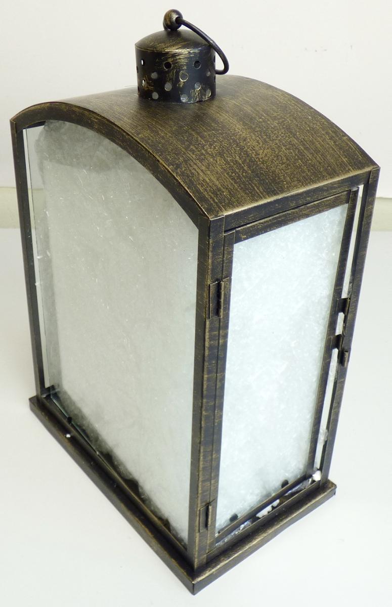 Bei der sog. Metall-Laterne, NAN: 8424771 handelt es sich um eine viereckige, ca. 27 cm x 16 cm x 39 cm (L x B x H) große Laterne, bestehend aus einem Metallgestell (lt. Antrag Eisen) mit einer Grundplatte und mit eingesetzten Seitenscheiben aus Glas, sowie einem Metalldach mit Tragegriff.
Eine Seite fungiert als Tür zum Einstellen eines Teelichtes oder einer Kerze.
Das Dach ist im oberen Bereich mit Belüftungslöchern versehen, die zur Abführung von Wärme und Rauch dienen.

Hinweise auf eine Handarbeit liegen nicht vor.

Die Ware ist als "nicht elektrischer Beleuchtungskörper, anderweit weder genannt noch inbegriffen, nicht handgearbeitet" einzureihen.
