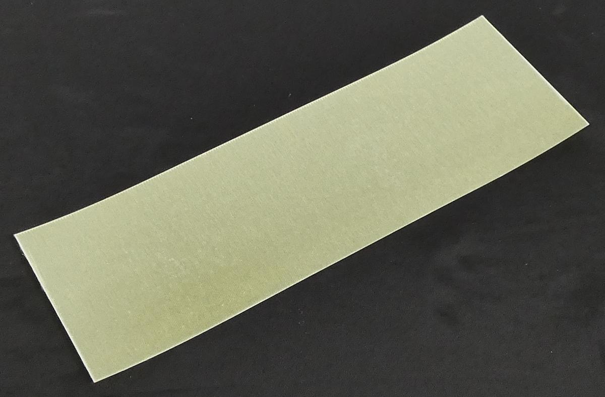 Angaben:
Es handelt es sich um ein Glasgewebe, das mit Epoxidharz beschichtet ist.

Feststellungen:
Es wurde ein weißes Gewebe vorgelegt, das beidseitig mit einem gelblichen, spröden, brüchigen Material beschichtet ist.

Befund:
Andere Folie aus Kondensationspolymerisations- oder Umlagerungspolymerisationserzeugnissen