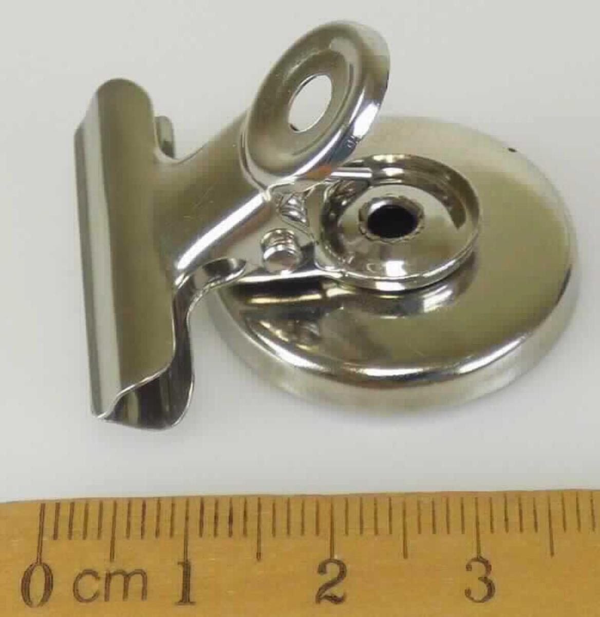Es handelt sich um aus verschiedenen Bestandteilen zusammengesetzte Waren, bestehend aus einer zweiteiligen Klammer aus unedlem Metall, die an einem kreisrunden Metallfuß mit integriertem Dauermagneten befestigt ist. Die Erzeugnisse können an magnetischen Oberflächen angebracht werden, dienen zum Halten z.B. von Notizzetteln, Fotos oder Karten und sind zu jeweils zwölf Stück in einem bedruckten Pappkarton verpackt.
Durchmesser: 2,8 cm
- Antragstellerangaben -

Der wesentliche Charakter der aus verschiedenen Bestandteilen zusammengesetzten Waren wird insbesondere in Bezug auf die Bedeutung für die Verwendung durch die Klammer bestimmt.

Abbildung siehe Anlage.

Derartige Erzeugnisse gehören als "den Briefklammern und Aktenklammern ähnliches Büromaterial, aus unedlen Metallen" zum TARIC-Code 8305 9000 00.