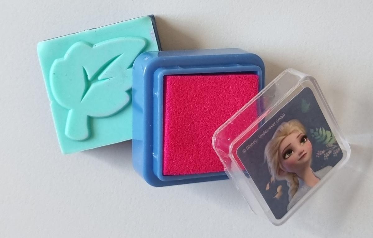 Es handelt sich um eine zusammengesetzte Ware in Form eines Stempelkissens mit einem Stempel.
Das mit Farbe getränkte Stempelkissen besteht aus saugfähigem Material und befindet sich in einem Kunststoffkästchen mit abnehmbarem Deckel; Seitenlänge 2,5 cm x 2,5 cm.
Unter das Kästchen ist in eine Aussparung passgenau ein herausnehmbarer Stempel (mit Blattmotiv) für den Handgebrauch eingesetzt.
Da weder das Stempelkissen aufgrund des höheren Wertes, noch der Stempel aufgrund seiner längeren Lebensdauer den Charakter der zusammengesetzten Ware bestimmt, erfolgt eine Einreihung in die zuletzt genannte, der gleichermaßen in Betracht kommenden Positionen.
Das Stempelkissen mit einem Stempel ist Bestandteil einer Zusammenstellung von Waren (Überraschungstüte) und ist gemeinsam mit vier Wachsmalkreidestiften, zehn bedruckten Papierbögen zum Ausmalen und einem Stickerbogen in einem mit Produktinformationen bedruckten Beutel aus Kunststofffolie verpackt. Eine Einreihung aller Bestandteile als Warenzusammenstellung kommt nicht in Betracht, da die Waren weder zur Befriedigung eines speziellen Bedarfs noch zur Ausübung einer bestimmten Tätigkeit zusammengestellt worden sind.

Abbildungen siehe Anlagen.

Derartige Waren gehören als "Stempelkissen, auch getränkt" zum TARIC-Code 9612 2000 00.