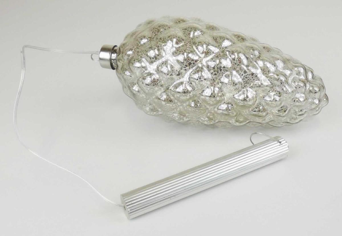 Ziergegenstand aus lampengeblasenem (gesponnenem) Glas, sog. Glaszapfen, Foto siehe Anlage,
- in Form einer zusammengesetzten Ware, bestehend aus:
- - einem oben offenen, zapfenförmigen, ca. 20 cm langen Hohlkörper aus Glas:
- - - laut Antrag aus lampengeblasenem Glas,
- - - innen teilweise (mit Aussparungen) silberfarben verspiegelt,
- - einem Krönchen aus unedlem Metall:
- - - den Abschluss des Zapfens bildend,
- - einem elektrischen Beleuchtungskörper: 
- - - in Form einer LED-Lichterkette, die ebenfalls in den Glaszapfen eingelegt ist,
- - - mit einer ca. 40 cm langen Zuleitung, die am oberen Ende mit einem integrierten Batteriefach und einem 
      Ein-/Ausschalter ausgestattet ist; am Ende des Batteriefachs mit einer Aufhängevorrichtung versehen,
- stellt sich insgesamt nicht als Beleuchtungskörper der Position 9405 dar, da die LED-Lichterkette im einge-
  schalteten Zustand lediglich die Zierwirkung des (charakterbestimmenden) Zapfens erhöht, die auch im
  ausgeschalteten Zustand gegeben ist,
- in einer Blisterverpackung.

"Ziergegenstand aus lampengeblasenem (gesponnenem) Glas"