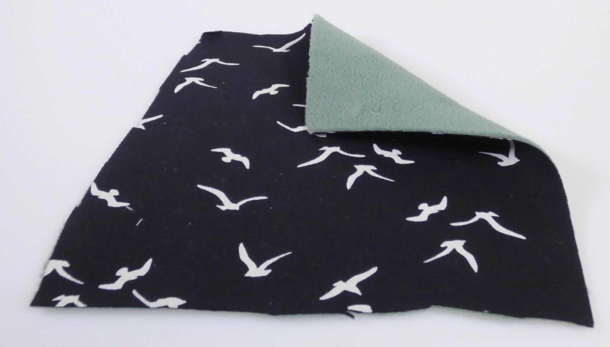 Kleidung, sog. Single Jersey Jacke, Größe S, Foto siehe Anlage,
- aus ca. 1,5 mm dicken, zweilagigen, durch Kleben miteinander verbundenen Flächenerzeugnissen, mit einer
  Außenlage aus bedruckten Gewirken aus laut Antrag 100 % Baumwolle und einer Innenlage aus einfarbigen,
  einseitig (Außenseite) gerauten Gewirken aus laut Antrag 100 % Polyester (synthetische Chemiefasern),
- hinten über den halben Oberschenkel reichend (Rückenlänge: ca. 92 cm), somit nicht nur den Oberkörper 
  bedeckend (u. a. damit keine Windjacke, Jacke oder Strickjacke); hinten abgerundet, vorn gerade und 
  bis zu ca. 7 cm kürzer gearbeitet, somit nicht bis zum halben Oberschenkel reichend (u. a. damit kein Mantel),
- mit Stehkragen,
- vorn mit einer durchgehenden Öffnung mit einem bis zum Kragenrand reichenden Reißverschluss, am
  Kragenrand mit einer kurzen Überlappung von links auf rechts (Männerkleidung, u. a. somit kein Kleid),
- mit langen Ärmeln, an den Ärmelenden mit angesetzten, verengenden Bündchen,
- mit einem verengenden Tunnelzug in der Taille,
- mit zwei eingesetzten, offenen Taschen unterhalb der Taille,
- am unteren Rand durch Umschlagen und Festnähen gesäumt,
- insbesondere im Hinblick auf das äußere Erscheinungsbild bilden die Gewirke aus Baumwolle das für die 
  Spinnstoffermittlung maßgebende Flächenerzeugnis.

"Kleidung, andere als in den Positionen 6101 bis 6113 genannte, aus Gewirken, aus Baumwolle"