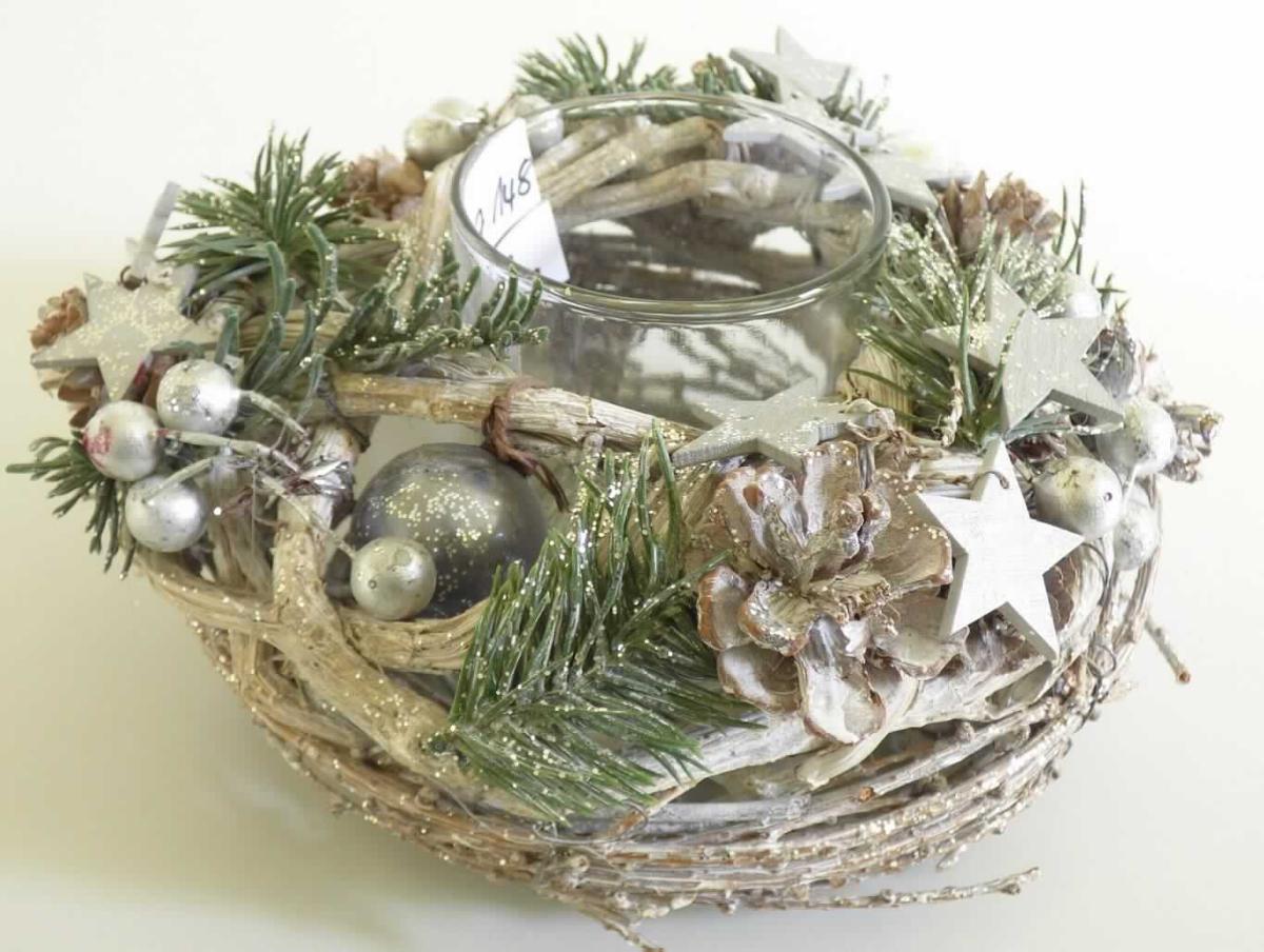 Nach den Antragsangaben sowie dem vorliegenden Warenmuster handelt es sich bei dem sog. "Kranz mit Teelicht, Order 10277146" um eine runde, oben offene Halterung (Ø ca. 17 cm; Höhe ca.10 cm), in die ein einfaches, klarsichtiges Glasgefäß (Ø ca. 6,5 cm; Höhe ca. 8 cm) passgenau eingestellt ist. Der Halter besteht aus einem Metallgestell, welches blickdicht mit beglitterten pflanzlichen Stoffen (überwiegend biegsame dünne Zweige, kein Rattan oder Bambus; Flechtstoffe i. S.d. Anmerkung 1 zu Kapitel 46) in Flechttechnik umwunden/umflochten ist. Die Flechtstoffe sind zusätzlich mit dünnem Draht befestigt. An der Außenseite sind einige kleine Holzsterne, natürliche Kiefernzapfen und silbergraue Kunststoffkugeln zur Verzierung angebracht.

Derartige Waren werden üblicherweise in der Winterzeit zur Dekoration verwendet.

Die pflanzlichen Flechtstoffe verleihen der Ware auf Grund des Umfangs und der Bedeutung in Bezug auf die Verwendung den wesentlichen Charakter.

Hinweise auf eine Fertigung in Handarbeit liegen nicht vor.

Zolltarifrechtlich handelt es sich um eine "Flechtstoffware, unmittelbar aus pflanzlichen Flechtstoffen hergestellt, nicht aus Bambus oder Rattan, keine Flaschenhülsen aus Stroh, nicht handgearbeitet".