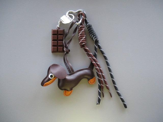 Es handelt sich um einen sog. „Taschenanhänger“, bestehend aus:
- einem herzförmigen Karabinerhaken aus unedlem Metall, hier Aluminium
   und daran angebracht
- ein stilisierter dekorativer Hunde-Anhänger aus zwei miteinander vernähten Kunststofffolien 
  mit lederartiger Haptik, einer Anhängeschlaufe und einem kleinen runden Anhänger aus 
  unedlem Metall,
- zwei geflochtene Seile, die jeweils in der Art eines Galgenknotens verknotet 
  sind und
- ein Anhänger in Form einer stilisierten Tafel Schokolade
Das Erzeugnis ist auf einer rechteckigen und bedruckten Pappkarte aufgemacht
Der Anhänger ist dazu gedacht zu dekorativen Zwecken als Accessoire mit dem Karabinerhaken an eine Tasche oder an einen Schlüsselbund gehängt zu werden.
- Angaben laut Antragsteller -

Bei dem aus verschiedenen Stoffen zusammengesetzten Erzeugnis sind die unedlen Metalle, insbesondere aufgrund der verbindenden und auch dekorativen Funktion des herzförmigen Karabinerhakens, charakterbestimmend im Hinblick auf die Verwendung.
Aluminium überwiegt gewichtsmäßig gegenüber anderen unedlen Metallen.

Abbildung siehe Anlage.

Derartige Erzeugnisse gehören als "andere (als in den TARIC-Codes 7616 1000 10 bis 7616 9990 91 genannte) Waren aus Aluminium" zum TARIC-Code 7616 9990 99.