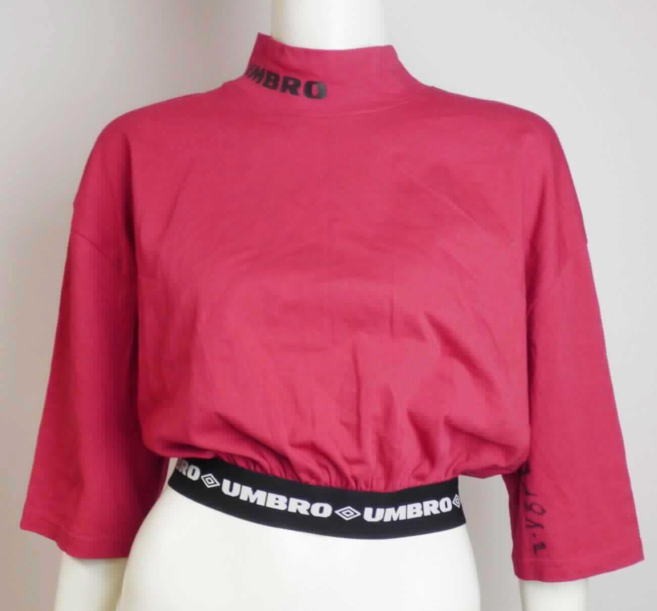 Pullover, sog. Umbro Migra SS Tee, Größe S, Foto siehe Anlage, 
- aus ca. 0,6 mm dicken, einfarbigen Gewirken aus laut Antrag 95 % Baumwolle und 5 % Elasthan (synthetische 
  Chemiefasern),
- über die Taille reichend (Rückenlänge: ca. 45 cm), 
- mit einem angesetzten, hohen Kragen (u. a. somit kein T-Shirt),
- ohne Öffnung und ohne Verschluss,
- ohne Hinweise auf den Trägerkreis (unisex),
- mit kurzen Ärmeln,
- nicht enganliegend gearbeitet (somit kein Unterziehpulli),
- am unteren Rand mit einem angesetzten, ca. 4 cm breiten, elastischen Bund verengt.

"Pullover, aus Gewirken, aus Baumwolle, kein Unterziehpulli, für Frauen"