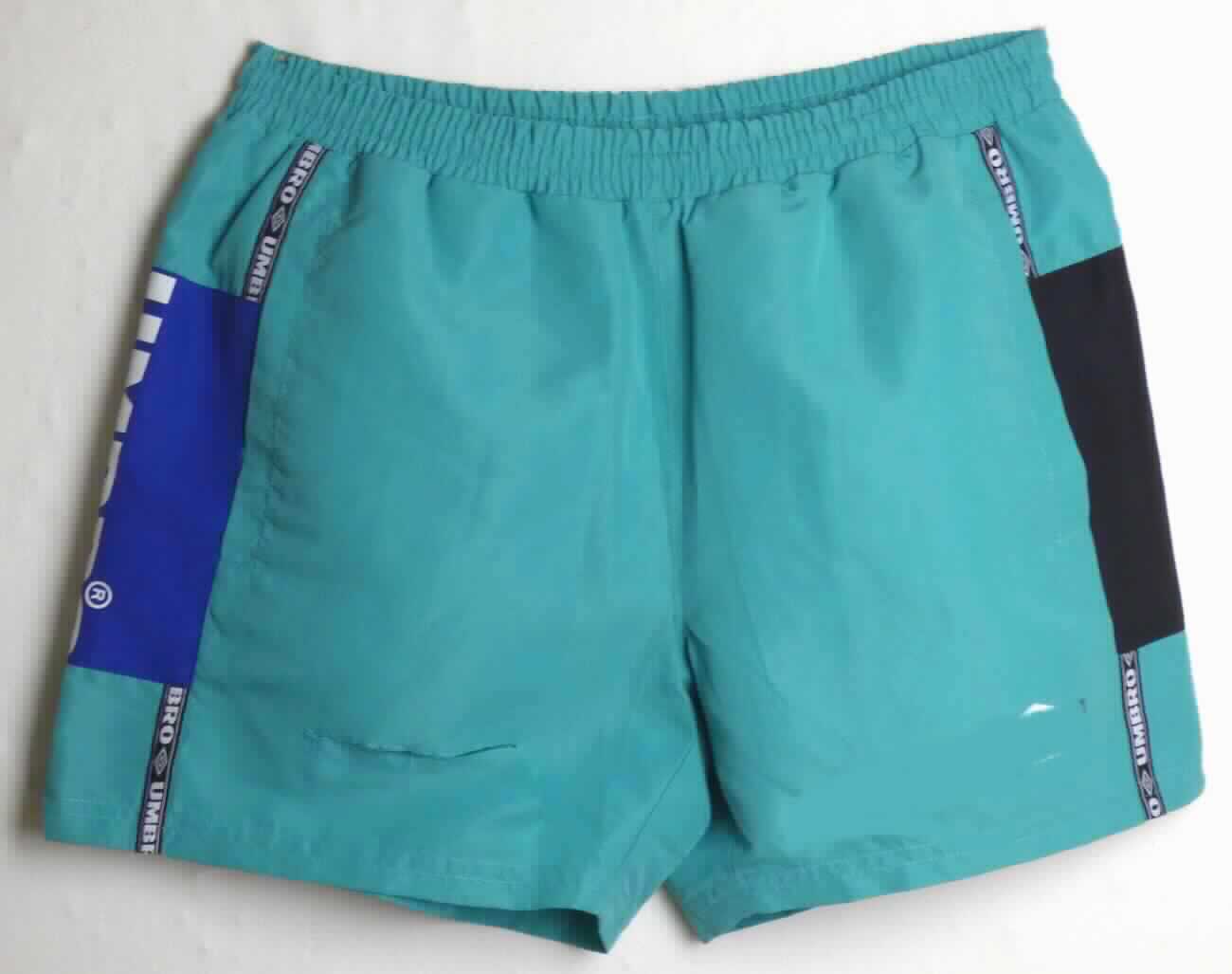Kurze Hose, sog. Umbro Horizon Swim Short UMSH0076, Größe M, Foto siehe Anlage,
- aus ca. 0,2 mm dicken, einfarbigen Geweben aus laut Antrag 100 % Polyester (synthetische Chemiefasern),
- in der Taille abschließend, mit einem angesetzten, elastischen Taillenbund mit Tunnelzug,
- ohne Öffnung und ohne Verschluss,
- ohne Hinweise auf den Trägerkreis (unisex), 
- mit einem Innenslip ausgestattet,
- vorn mit zwei eingesetzten, offenen Seitentaschen (somit keine Badehose),
- mit aufgenähten Streifen und Zuschnitten aus buntgewebten bzw. bedruckten Geweben verziert,
- mit kurzen Hosenbeinen, die nicht die Knie bedecken (Seitenlänge: ca. 38 cm),
- an den Beinabschlüssen durch Umschlagen und Festnähen gesäumt.

"Kurze Hose, aus Geweben, für Frauen, aus synthetischen Chemiefasern, nicht nach dem Batik-Verfahren
 handbedruckt"