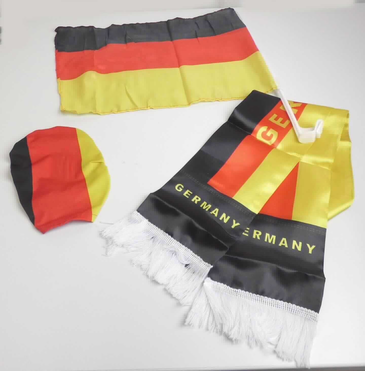 Zusammenstellung, bestehend aus einem Fan-Schal, zwei Autoflaggen und zwei Außenspiegelüberzügen, sog. Fan-Set, Foto siehe Anlage,
- in einer gemeinsamen Umschließung (Polybeutel) für den Einzelverkauf aufgemacht,
- die Waren dienen weder der Befriedigung eines speziellen Bedarfs noch der Ausübung einer bestimmten
  Tätigkeit und stellen somit keine Warenzusammenstellung im Sinne der AV 3 b) dar; somit sind die drei 
  Warengruppen getrennt voneinander einzureihen, 
- Fan-Schal:
-- doppellagig; aus einem ca. 0,1 mm dicken, bedruckten (schwarz-rot-gold; mehrere Schriftzüge "GERMANY") 
   Gewebe aus augenscheinlich synthetischen Chemiefasern,
-- an einer Längsseite zusammengenäht, an den Schmalseiten mit zusätzlich aufgenähten Fransen verziert
   (u. a. damit konfektioniert),
-- in den Abmessungen von ca. 145 cm x 14 cm,
-- ohne Hinweise auf Handarbeit.

"Schal, aus Geweben, aus synthetischen Chemiefasern, nicht handgearbeitet"
