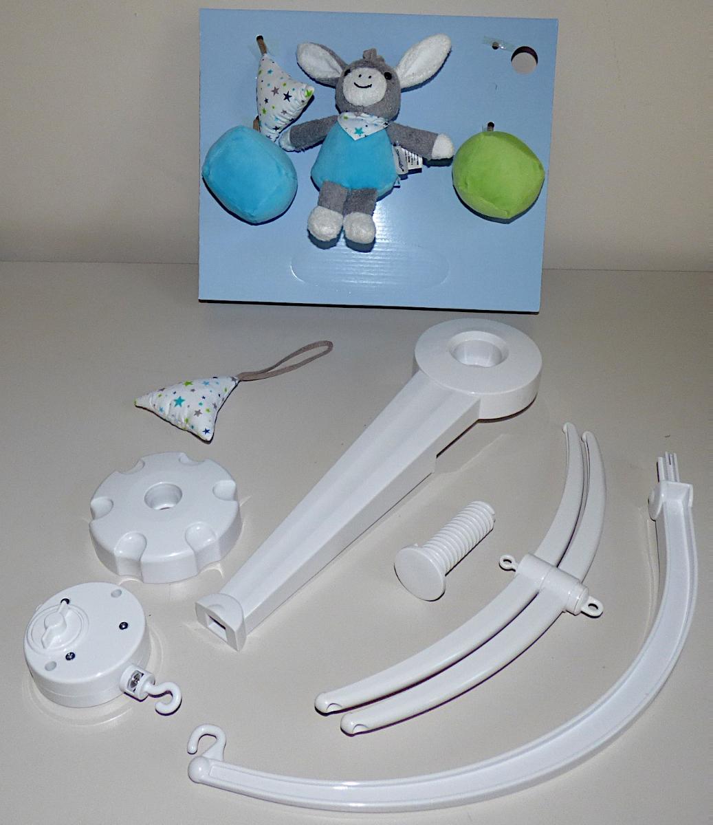 Bei dem durch Beschreibung sowie ein Warenmuster veranschaulichten Erzeugnis handelt es sich um ein noch nicht zusammengesetztes und aus verschiedenen Bestandteilen bestehendes Musikmobile für Kleinkinder, sog. "Mobile, Art. 6101731", bestehend aus
- einer Halterung aus Kunststoffen mit Schraubbefestigung zur Befestigung an z.B. einem Kinderbett,
- einem Haltebogen aus Kunststoffen,
-- am unteren Ende mit einer Befestigungsnase zum Einschub in die Halterung und an der oberen Seite mit einem ausgearbeiteten Haken versehen,
- einer Spieldose,
-- auf der Rückseite mit einem über einen Drehknopf aufziehbaren Federmechanismus versehen,
-- an der Oberseite mit einer Öse und an der Unterseite mit einem Haken ausgestattet,
-- soll zwischen der Halterung und dem Mobilekreuz eingehängt werden,
- einem Mobilekreuz mit zwei drehbaren Halbbögen aus Kunststoffen,
-- auf der Ober- und der Unterseite mit einer Öse versehen,
-- an den Enden jeweils mit einer lochartigen Befestigungsvorrichtung versehen,
-- soll an der Spieldose aufgehängt werden,
- vier weich befüllten Anhängern aus Spinnstoffen (zwei Dreiecke und zwei Würfel) mit Spinnstoffschlaufen und einer Tierfigur (stilisierter Esel) mit einer Spinnstoffschlaufe,
-- die Anhänger sollen mit Hilfe der Spinnstoffschlaufen an den Enden des Mobilekreuzes und die Tierfigur an der unteren Öse des Mobilekreuzes befestigt werden,
- dient der spielerischen Unterhaltung von Babys und Kleinkindern,
- gemeinsam mit einer Aufbauanleitung in einem Pappkarton mit Sichtfenster für den Einzelverkauf aufgemacht.

Durch Aufziehen der Spieldose wird eine Melodie abgespielt und das Mobile gleichzeitig gedreht.

Der Unterhaltungswert wird hauptsächlich von der Spieldose bestimmt, die aufgrund des Mobiles Spielzeugcharakter erhält und innerhalb der zusammengesetzten Ware charakterbestimmend ist.

Das Erzeugnis ist zolltariflich als "Musikspielzeuggerät, keine handgearbeitete Ware aus Holz" einzureihen.