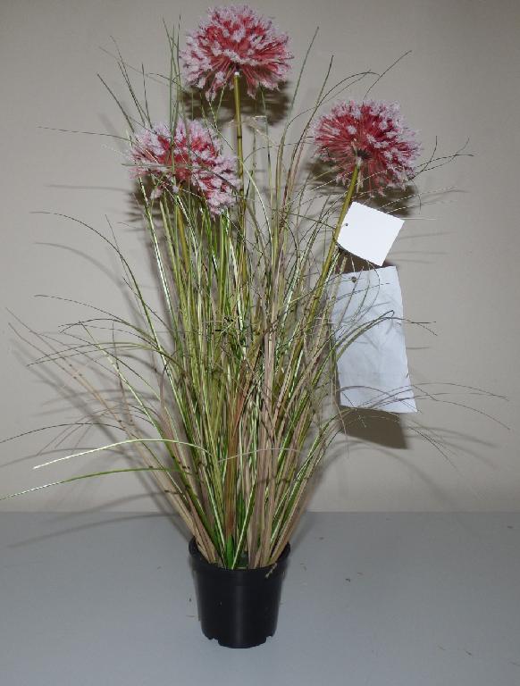 Ware aus künstlichem Blattwerk und künstlichen Blumen, sog. Kunstgras im Topf, Artikel 8731800,
7845601, Foto siehe Anlage,
- in Form einer aus verschiedenen Bestandteilen zusammengesetzten Ware, bestehend aus:
- - der Nachahmung von Zierlauch (künstliche Blumen):
- - - aus Stängeln aus Kunststoff; mit Metalldraht verstärkt,
- - - mit Blüten aus Kunststoff; jeweils im Spritzgussverfahren gefertigt; an den Enden mit aufgeklebten
       Fasern aus Spinnstoff,
- - - durch Zusammenstecken und Kleben in Blumenbindetechnik hergestellt,
- - der Nachahmung von Gräsern (künstliches Blattwerk):
- - - mehrere Stängel aus einer nach oben hin grasartig zugeschnittenen Kunststofffolie,
- - - am unteren Ende zusammengebunden, mit Metalldraht verstärkt sowie mit Papier umwickelt und
       dadurch in Blumenbindetechnik zusammengefügt,
- - einem schwarzen Blumenübertopf aus Kunststoff,
- - Nachahmung von Blumenerde:
- - - aus Kunststoff; in den Blumenübertopf eingeklebt,
- - - die Nachahmungen des Zierlauchs und der Gräser sind darin eingesteckt,
- - Styropor (Kunststoff); unterhalb der "Blumenerde" in den Blumenübertopf eingeklebt,
- das künstliche Blattwerk und die künstlichen Blumen bestimmen im Hinblick auf das
  Erscheinungsbild (Zierwirkung) den wesentlichen Charakter der Ware.

"Ware aus künstlichem Blattwerk und künstlichen Blumen, aus Kunststoff"