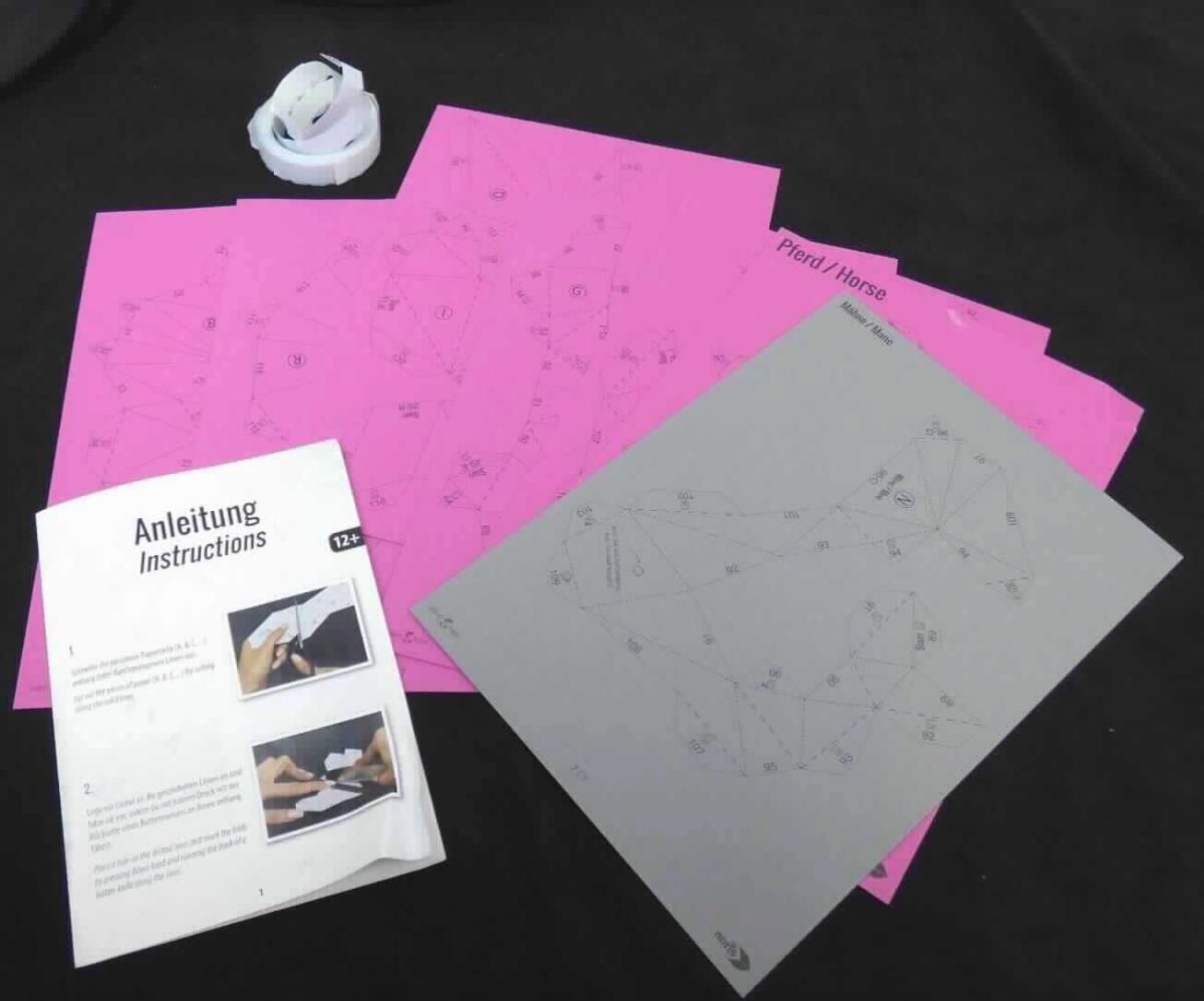 Bei dem vorgelegten Warenmuster handelt es sich um eine Zusammenstellung der nachfolgend beschriebenen Waren, die gemeinsam in einer mit warenbezogenen Hinweisen farbig bedruckten Stülpdeckelschachtel aus mit Papier beklebter Pappe für den Einzelverkauf aufgemacht sind: 

1. Sieben rechteckige, durchnummerierte Zuschnitte aus Kartonpapier (Format DIN A4), die jeweils auf beiden Seiten oberflächengefärbt (sechs mit pinker Farbe und einer mit grauer Farbe) sind. Sie sind einseitig mit nummerierten Schneide- und Falzlinien, Buchstaben, schlagwortartigen Hinweisen (z. B. "START" und "nach außen falten / fold outwards") sowie dem Logo der Antragstellerin und einem Markenlogo bedruckt. 

2. 500 rechteckige, etwa 1,2 x 1,3 cm große, beidseitig mit einer selbstklebenden Beschichtung versehene Zuschnitte aus Papier (sog. Klebepads), die auf einen silikonisierten Streifen aus Papier aufgebracht, jeweils mit einem Schutzpapier abgedeckt und in einem Behältnis aus mit warenbezogenen Hinweisen farbig bedrucktem Papier beklebter Pappe mit Entnahmevorrichtung verpackt sind. 

3. Ein beidseitig mit Text und Abbildungen bedruckter Zuschnitt aus Papier (Format DIN A4 quer, einmal auf etwa DIN A5 gefalzt). Er enthält im Wesentlichen eine illustrierte Schritt-für-Schritt-Gebrauchsanleitung für die unter 1. und 2. beschriebenen Erzeugnisse sowie einen QR-Code, über den man mit einem Smartphone ein Anleitungsvideo aufrufen kann. 
 
Abbildung siehe Anlage. 

Die einzelnen unter 1. beschriebenen Zuschnitte sollen unter Zuhilfenahme der unter 2. und 3. beschriebenen Waren so zugeschnitten, gefaltet und miteinander verklebt werden, dass ein dreidimensionaler, etwa 34,0 cm hoher Pferdekopf entsteht, der als Wanddekoration in Innenräumen (z. B. im Wohnzimmer) verwendet werden soll. 

Derartige Waren gehören als "andere als in den Unterpositionen 4811 10 bis 4811 60 genannte Papiere, auf der Oberfläche gefärbt, bedruckt, in rechteckigen Bogen, jeder Größe, ausgenommen Waren von der in der Position 4803, 4809 oder 4810 beschriebenen Art" zur Codenummer 4811 90 00 90 0 des Zolltarifs, da es sich zolltarifrechtlich um eine Warenzusammenstellung in Aufmachung für den Einzelverkauf handelt, deren wesentlicher Charakter im Hinblick auf die Bedeutung für die Verwendung durch die unter 1. beschriebenen Zuschnitte aus Kartonpapier bestimmt wird.
