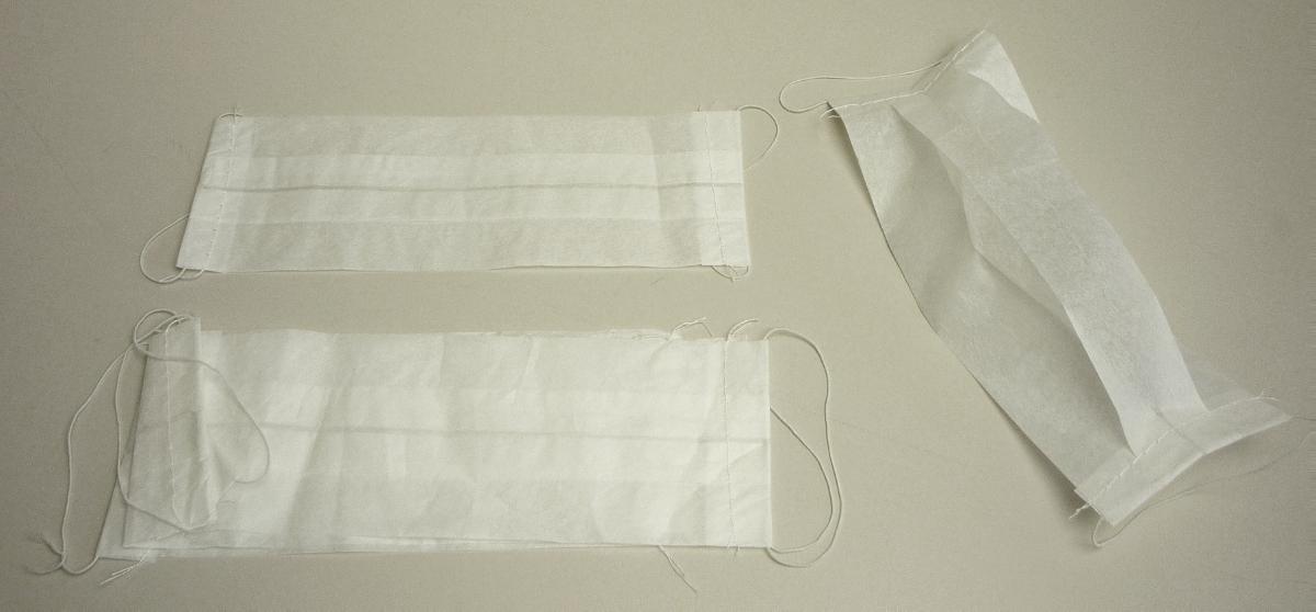 Bei dem als " Mundschutz weiss" bezeichneten Erzeugnis handelt es sich um einen einlagigen, dünnen, durchscheinenden und mehrfach auf etwa 19,2 x 6,9 cm gefalteten Zuschnitt aus einem Vlies aus Zellstofffasern. Die beiden Schmalseiten sind umgeschlagen und vernäht sowie je mit einer zum Fixieren an den Ohren bestimmten Schlaufe aus einem elastischen, verknoteten Band aus mit Baumwollfäden ummantelten Gummi ausgestattet. Das Erzeugnis soll als Mundschutz verwendet werden und ist zu 100 Stück in einer Spenderbox aus Pappe verpackt, von denen sich 100 Stück in einem Karton aus Wellpappe befinden.

Abbildung siehe Anlage.

Derartige Waren gehören als "den Taschentüchern ähnliche Waren zu hygienischen Zwecken, aus Vliesen aus Zellstofffasern, in Aufmachung für den Einzelverkauf" zum TARIC-Code 4818 9090 00.