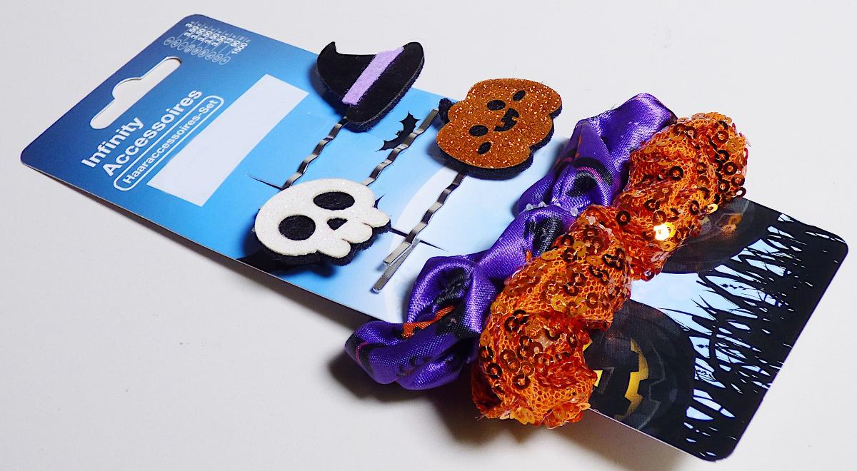 Bei dem sog. "Halloween Haaraccessoires-Set (Haargummi & Haarnadel), Art. 356920" handelt es sich um eine Warenzusammenstellung in Aufmachung für den Einzelverkauf, bestehend aus:
- drei Haarklammern mit je einem Motiv und
- zwei Haargummis aus elastischen und schlauchförmigen Schlingengewirken aus Spinnstoffgarnen.

Die Waren dienen zum Zusammenhalten des Haares. Im Hinblick auf die Menge bestimmen die Haarklammern den Charakter der Warenzusammenstellung. 

Die gemeinsam an einer Pappkarte befestigte Warenzusammenstellung ist als "Haarklammer, andere als Frisierkämme, Einsteckkämme, Haarspangen und dergleichen" einzureihen.