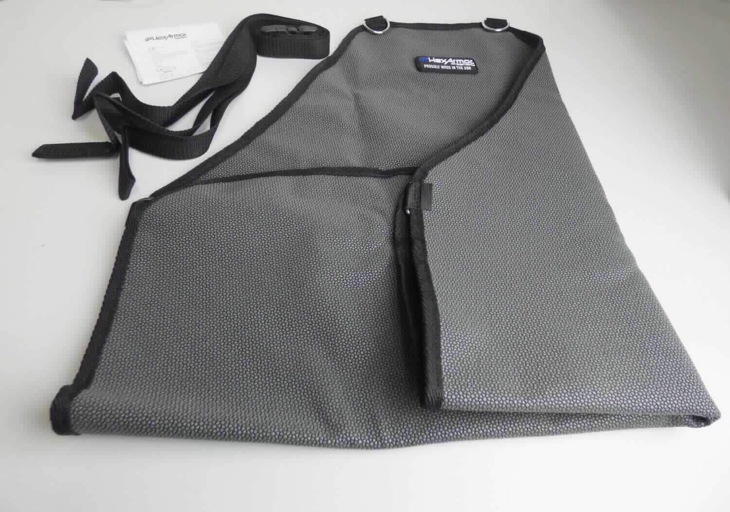 Schürze, sog. Schnittschutz-Schürze HexAmor Apron AP322, Materialnummer:6000100, in Erwachsenengröße, 
Foto siehe Anlage,
- in einem Polybeutel mit eingelegter Produktinformation verpackt,
- als Latzschürze gearbeitet; mit den Abmessungen von ca. 66 cm (Länge ohne Träger) x 61,5 cm (Breite),
- doppellagig, mit einer Außen- und Innenlage aus einfarbigen, auf der Außenseite musterbildend mit 
  Kunststoff bedruckten Geweben aus laut Antrag Polyester (synthetische Chemiefasern), 
- den vorderen Teil des Körpers bedeckend,
- mit zwei, im Rücken über Kreuz gelegten Trägern aus Gurten aus Geweben aus laut Antrag Polypropylen 
  (synthetische Chemiefasern), die am oberen Rand und in Taillenhöhe durch D-Ösen aus unedlem 
  Metall geführt werden; die Träger werden mittels Klettverschluss an den D-Ösen des oberen Randes 
  befestigt und im Rücken mittels einer Klickverschlussschnalle aus Kunststoff geschlossen sowie in der Länge 
  reguliert, 
- ohne Hinweise auf den Trägerkreis (unisex), 
- mit einer Randeinfassung aus einfarbigen Geweben aus Spinnstoffen,
- lässt erkennen, dass sie dazu bestimmt ist, ausschließlich oder hauptsächlich zum (körperlichen oder 
  hygienischen) Schutz anderer Kleidungsstücke und/oder Personen bei Ausübung einer Gewerbe-, Berufs- 
  oder Haushaltstätigkeit getragen zu werden.

"Andere Kleidung (Schürze), aus Geweben, für Frauen, aus Chemiefasern"